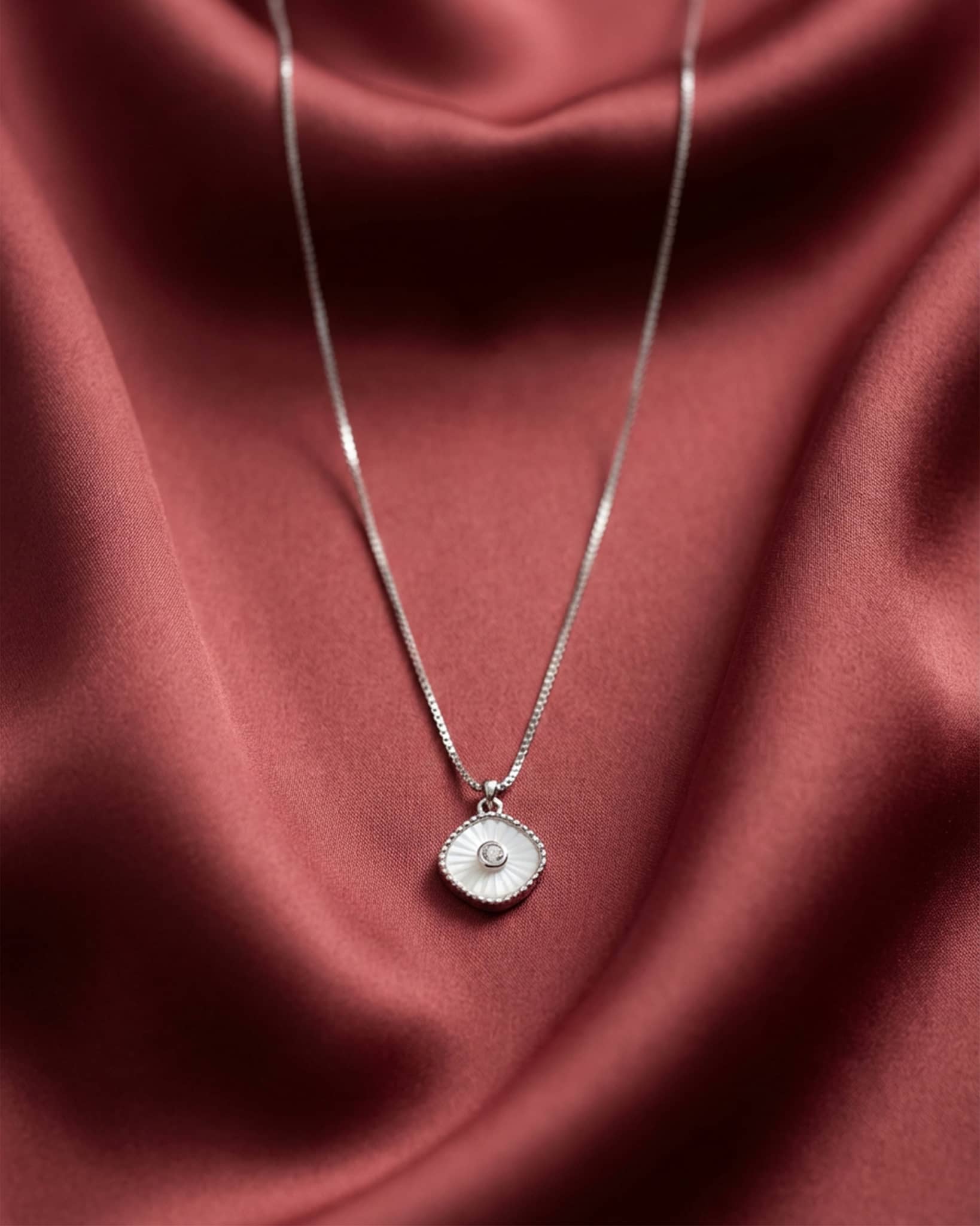 92.5 sterling silver necklace featuring a white cushion pendant with sunburst texture and cz center.