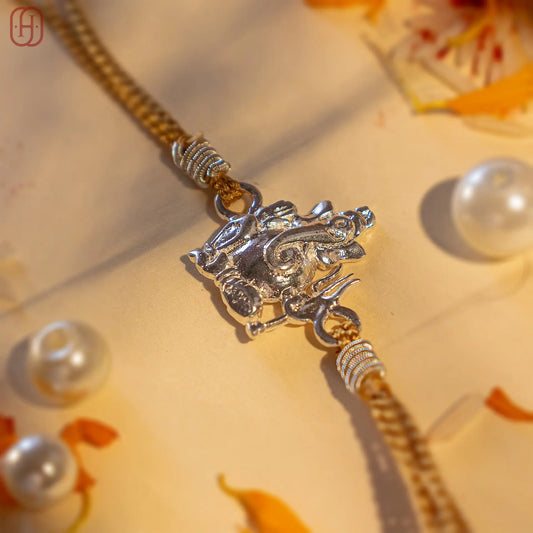 Ganesh silver rakhi with a detailed silver Ganesh pendant on a golden braided thread from Hardik Jewels