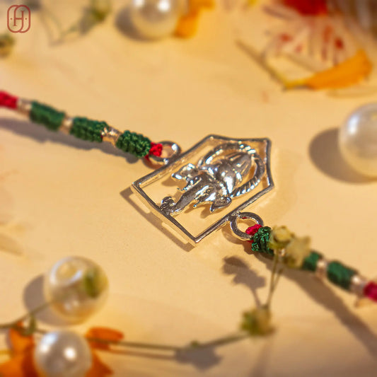 Silver Ganesh Ji face rakhi online with green and red braided thread from Hardik Jewels