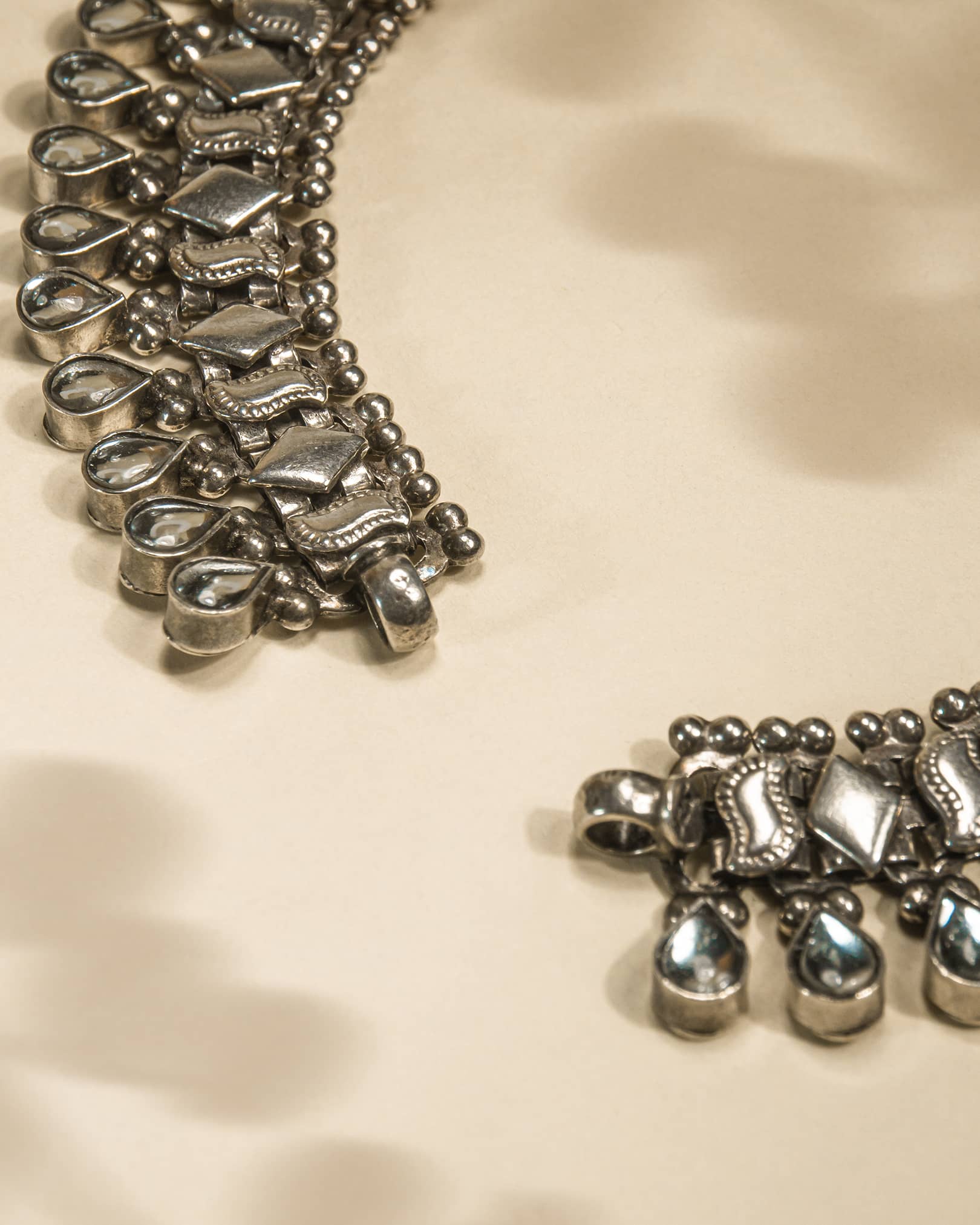 Close-up of a silver anklet on a beige fabric background