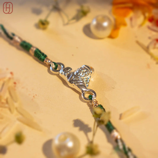 Sai Baba silver rakhi with detailed silver centerpiece and green thread by Hardik Jewels