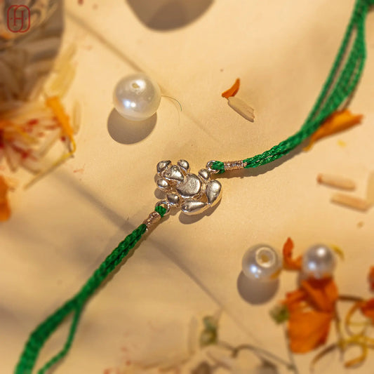 Ganesh Ji face silver rakhi online with green thread and silver charm by Hardik Jewels