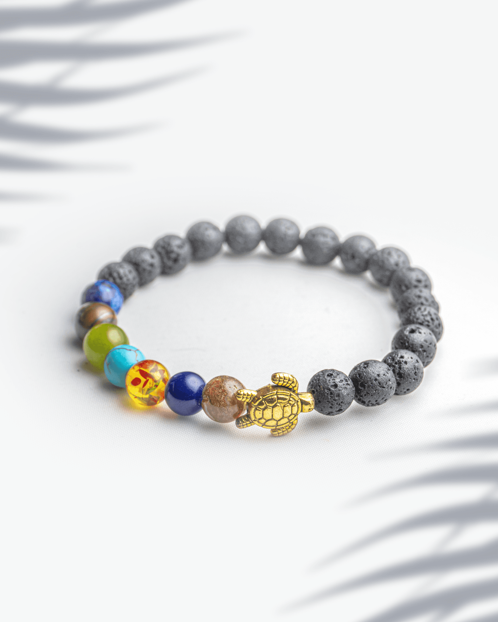 7 chakra healing bracelet with black lava stone beads and a golden turtle charm for good luck.