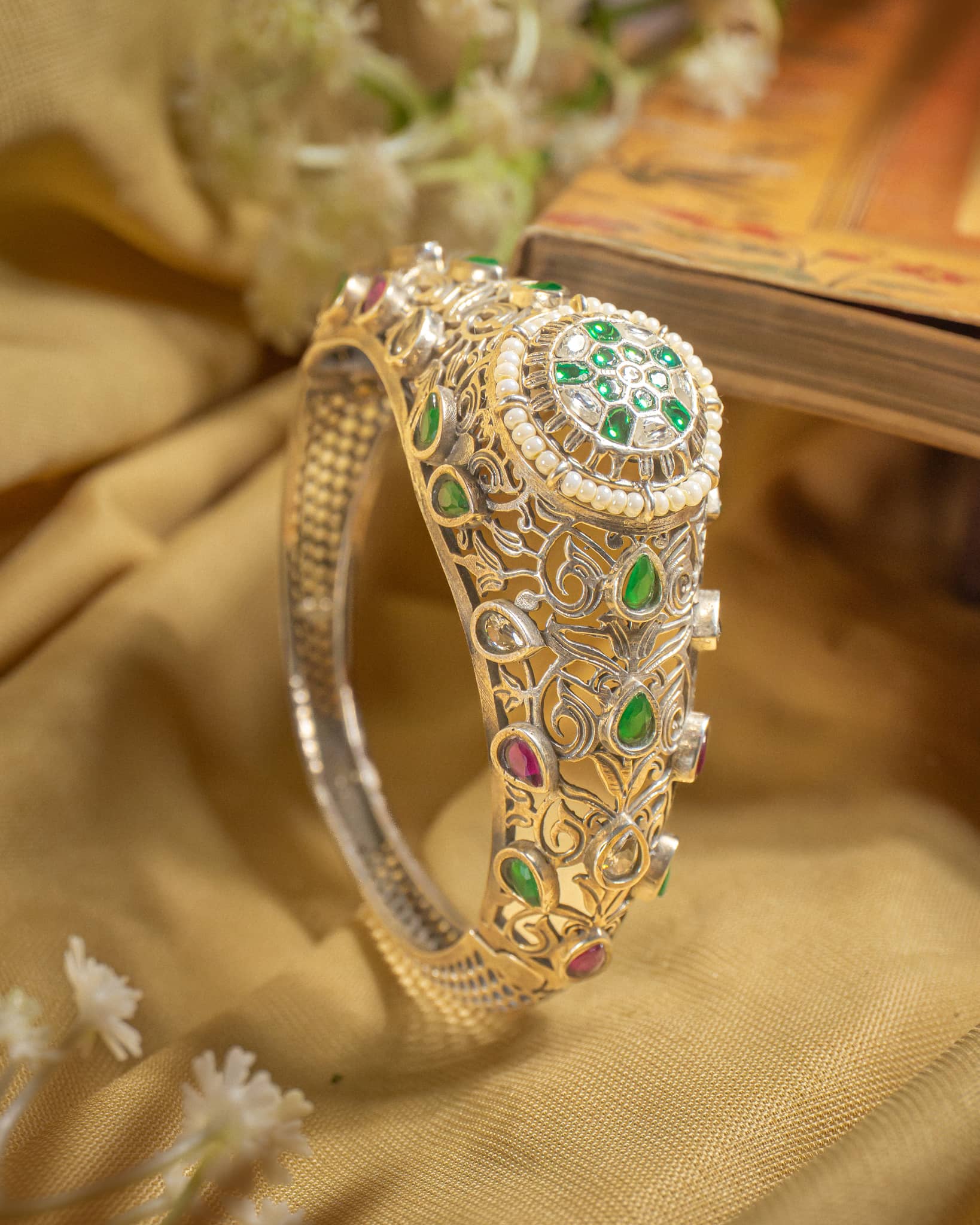 92.5 sterling silver jadau kundan bangle featuring floral motif with green red stones and pearls.