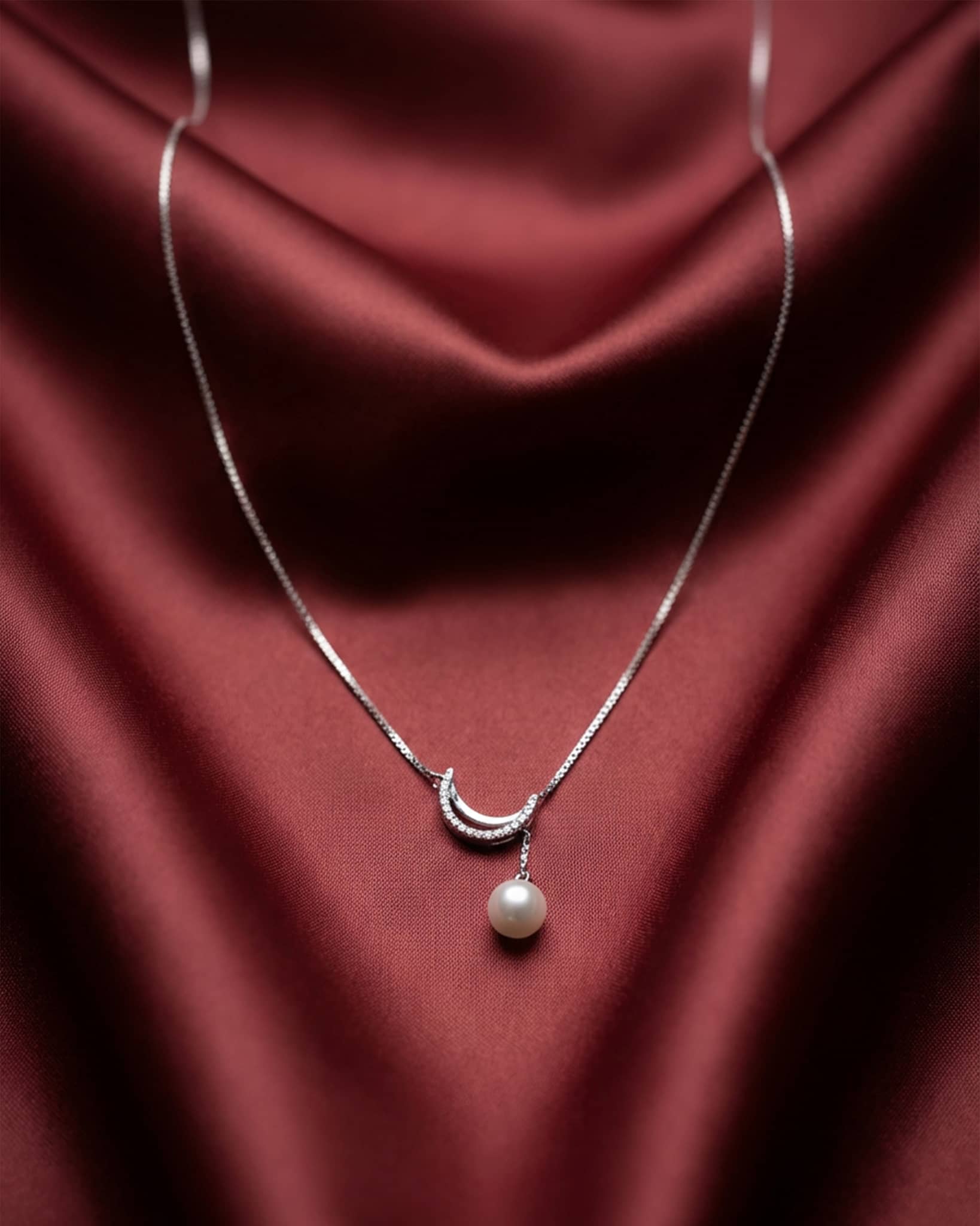 92.5 sterling silver necklace featuring a crescent moon pendant with a dangling white pearl.