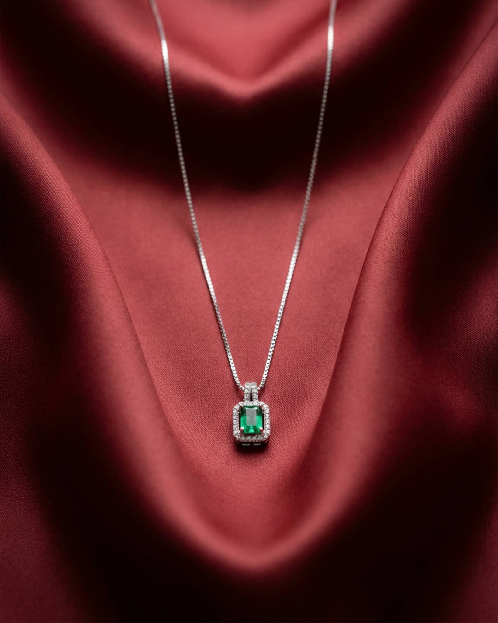 92.5 sterling silver necklace featuring a rectangular emerald green stone surrounded by a white diamond halo.