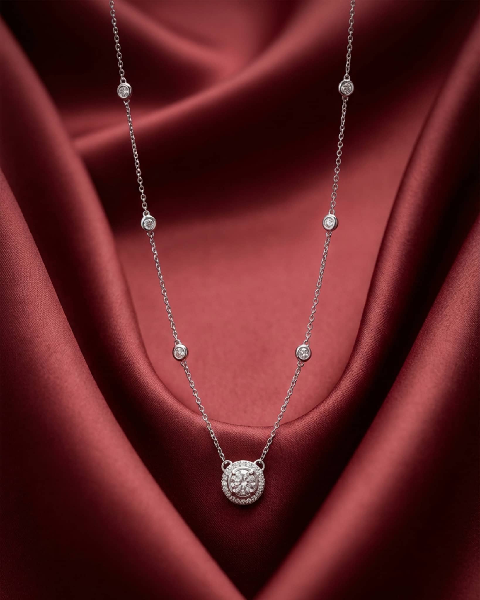 92.5 sterling silver necklace featuring a round solitaire halo pendant and bezel set stones on the chain.