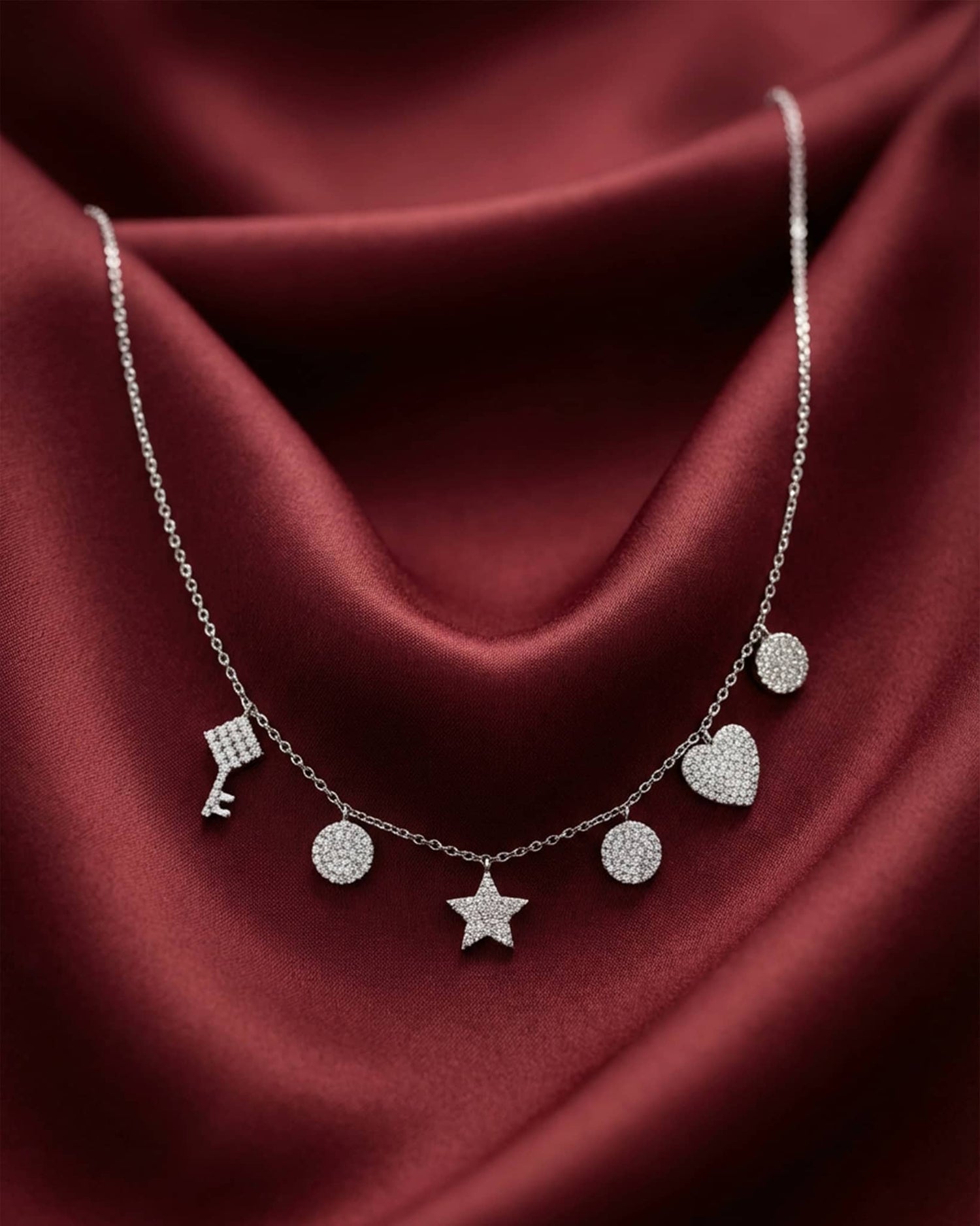 92.5 sterling silver necklace featuring dangling key star heart and disc charms studded with diamonds.
