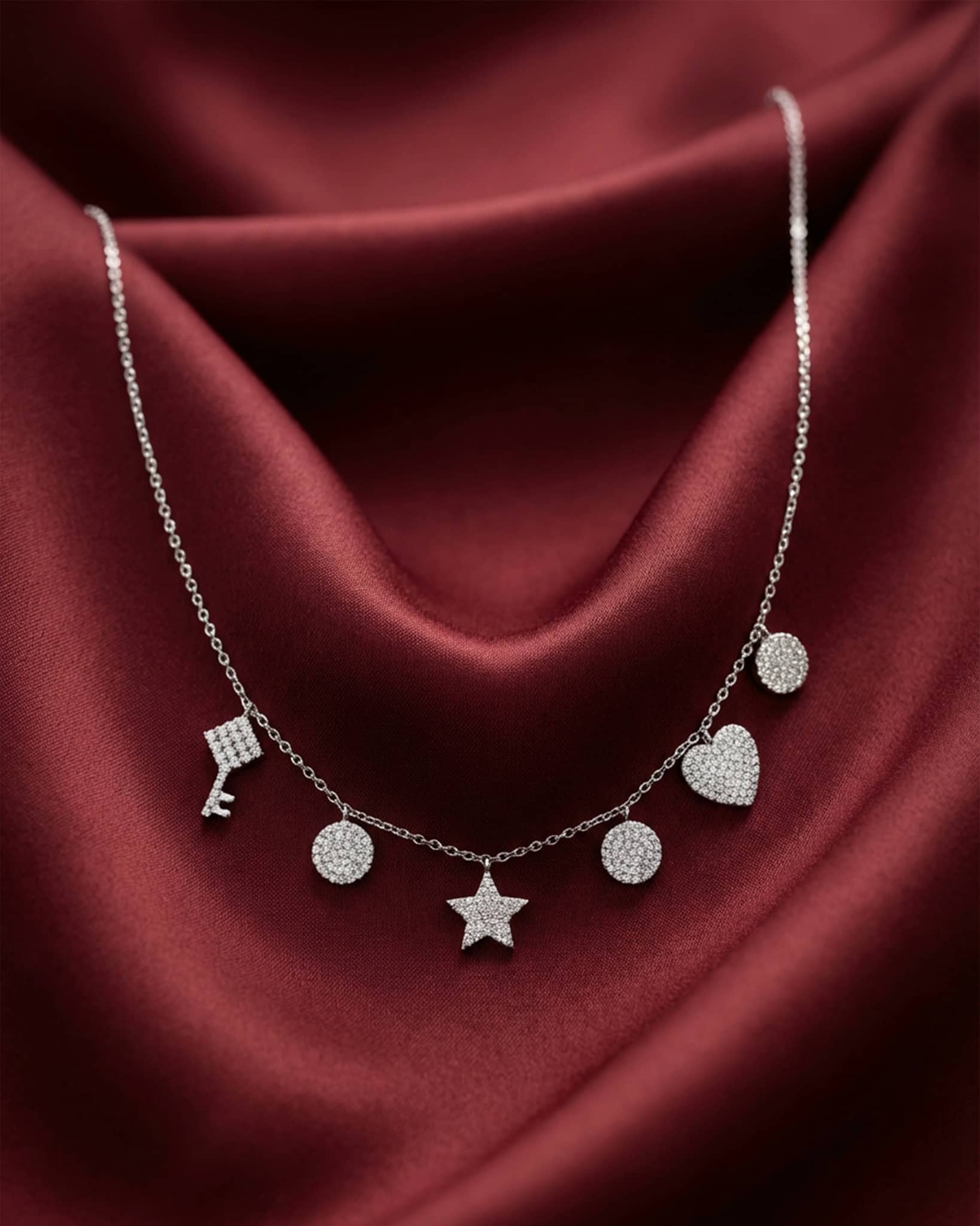 92.5 sterling silver necklace featuring dangling key star heart and disc charms studded with diamonds.