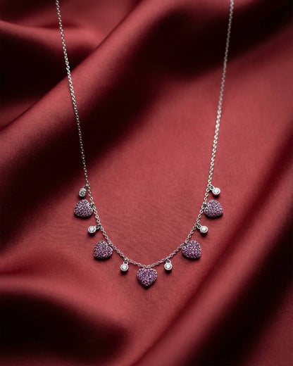 92.5 sterling silver necklace featuring dangling pink pave heart charms and white crystal stations.