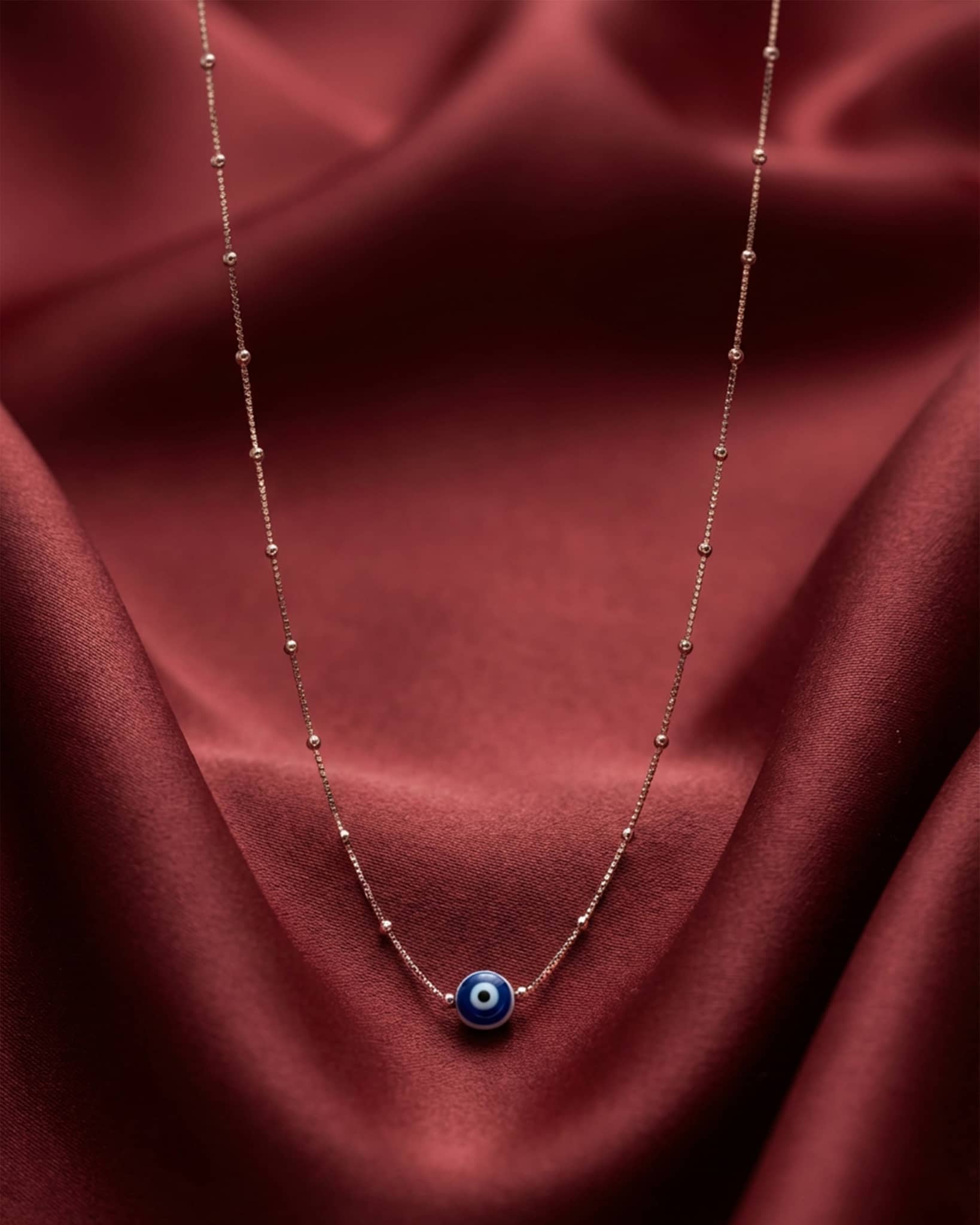 92.5 sterling silver rose gold plated necklace featuring a blue evil eye bead on a station chain.
