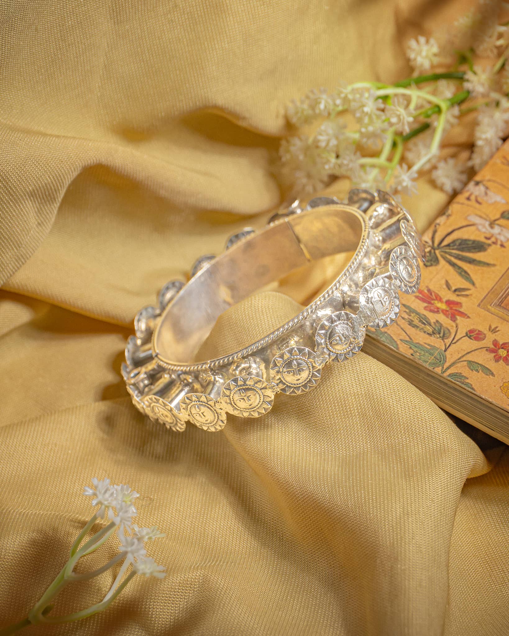 92.5 sterling silver wide bangle featuring embossed sun god surya face motifs.