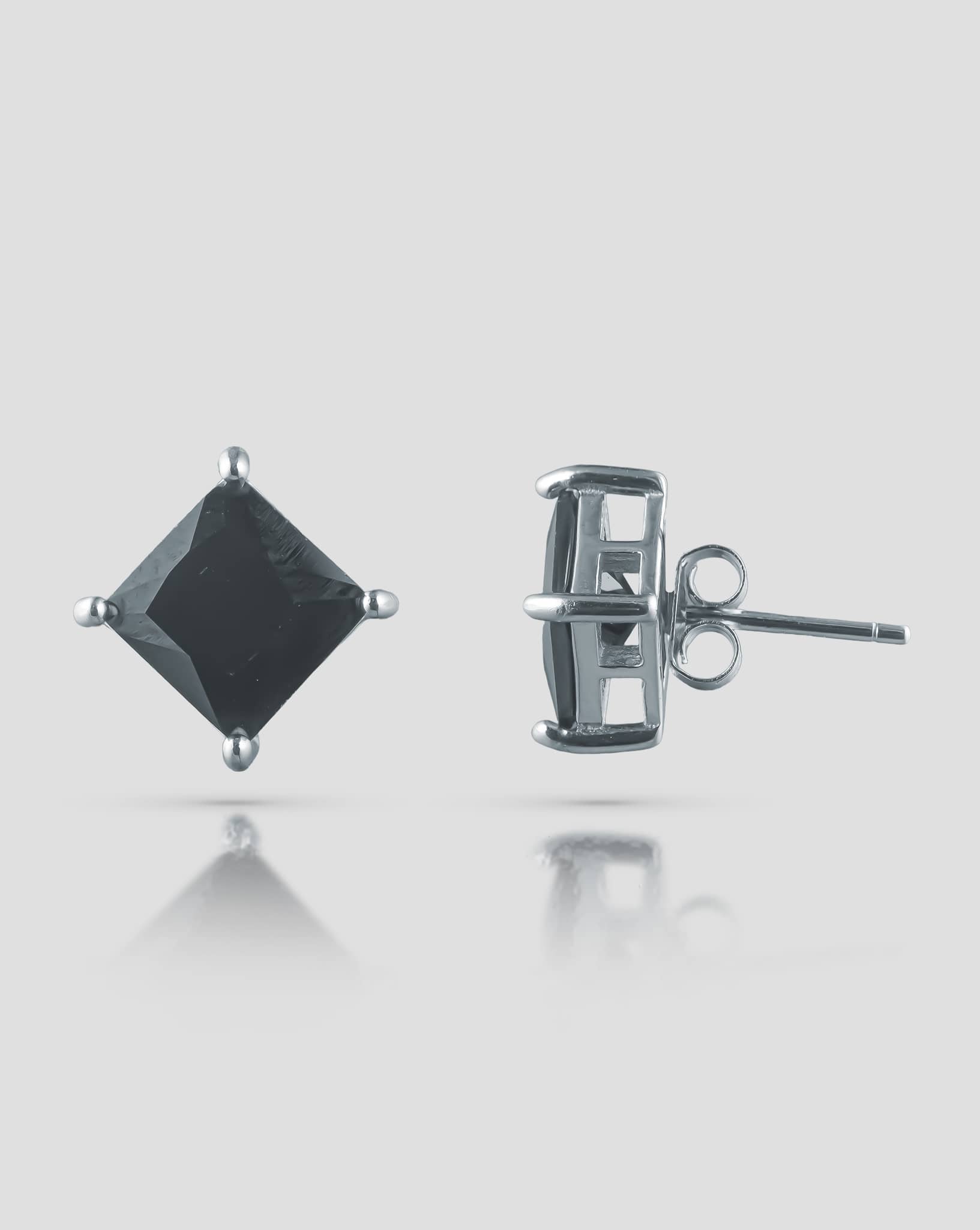Front and side profile view of silver stud earrings featuring a square black cz stone in a 4-prong basket setting with push-back closures