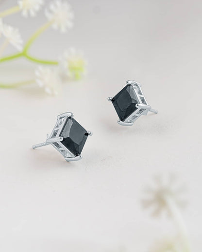 Floating angled shot of minimalist 92.5 sterling silver square black stud earrings highlighting the faceted dark stone and prong setting