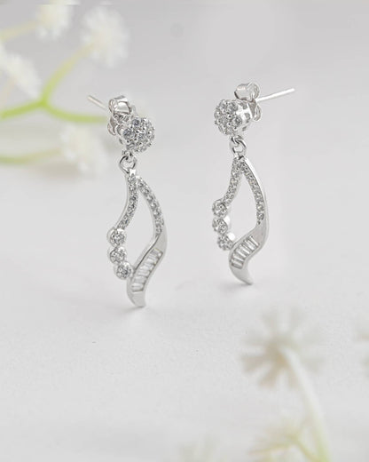 Floating angled shot of elegant 92.5 sterling silver open teardrop dangle earrings featuring a mix of sparkling round and baguette clear cz stones.
