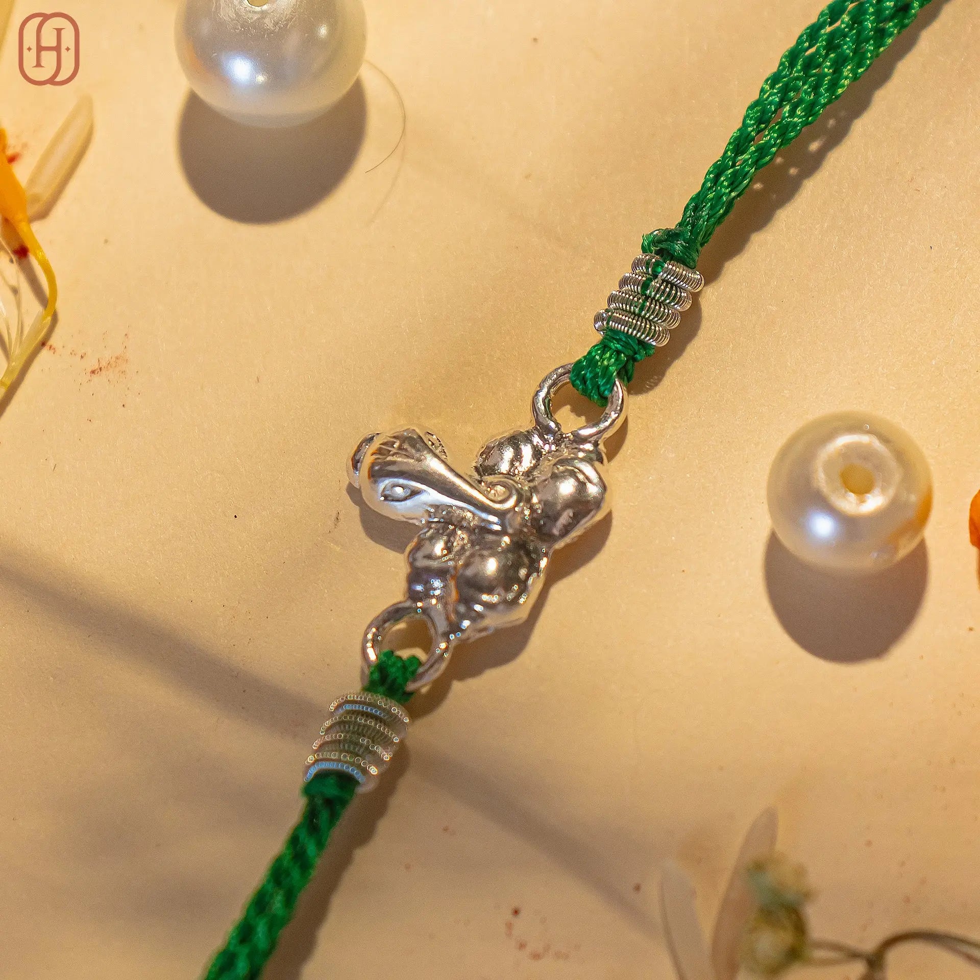 925 silver Ganesh Ji Rakhi with detailed silver Ganesh charm on green braided thread by Hardik Jewels