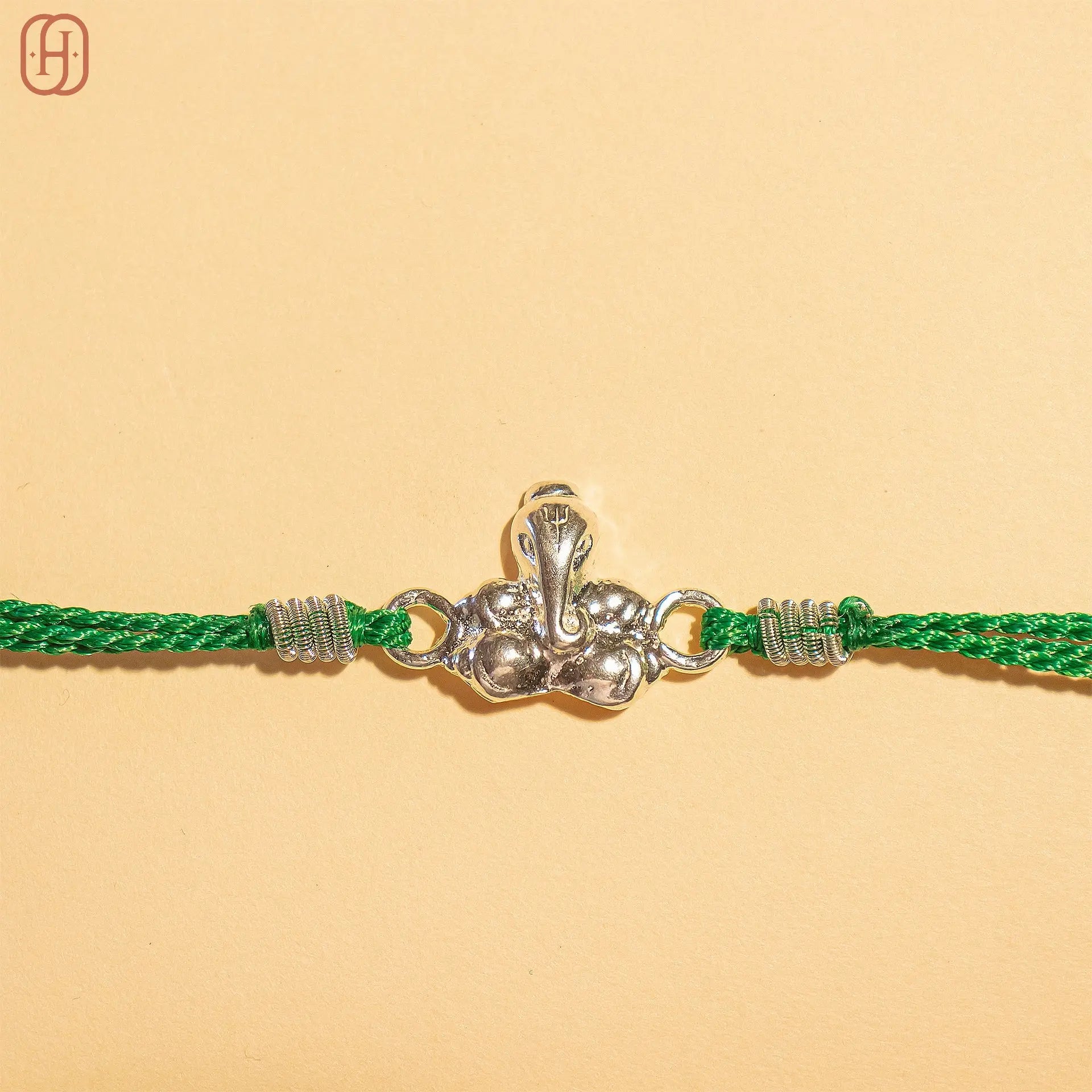 925 silver Ganesh Ji Rakhi with green thread and intricate silver Ganesh charm by Hardik Jewels