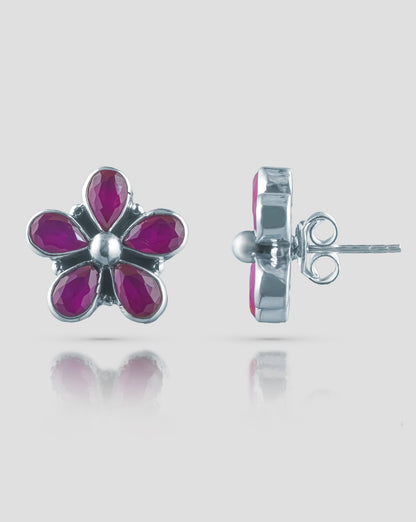 Floating angled shot of cute 92.5 sterling silver 5-petal flower stud earrings highlighting the vibrant ruby pink stones against a white background