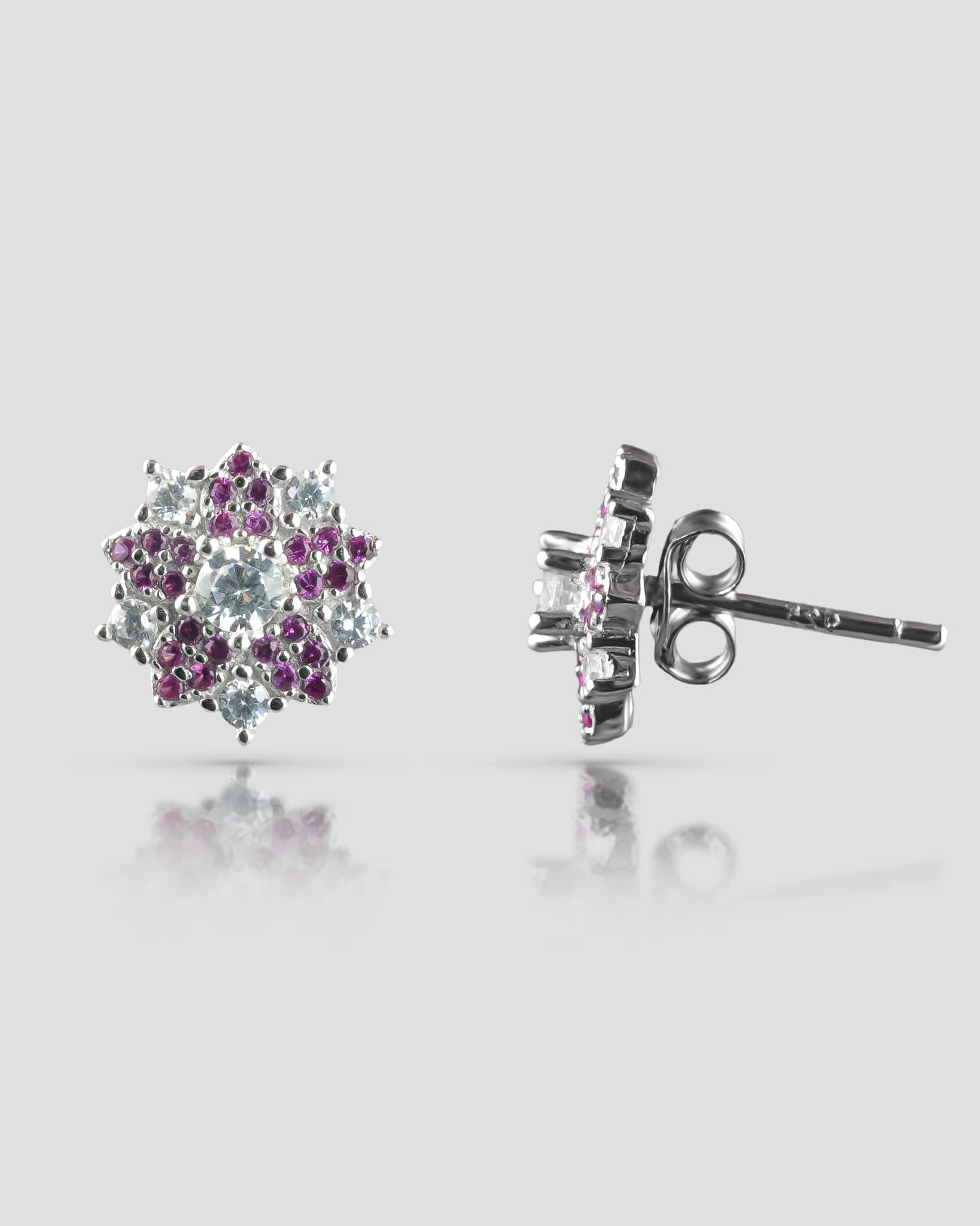 Front and side profile view of silver floral stud earrings showcasing a clear cz center, an inner ruby pink halo, and an outer clear cz petal halo with a push-back closure.