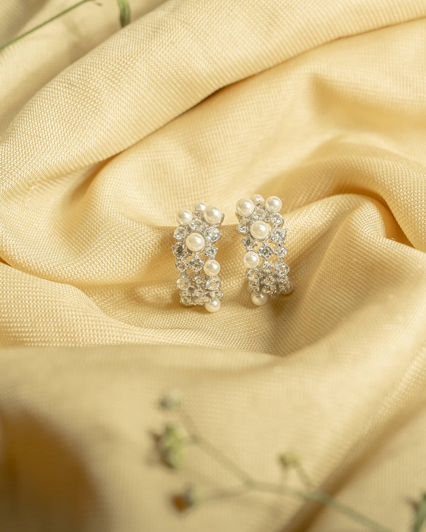 925 sterling silver broad hoop earrings studded with white pearls and american diamonds.