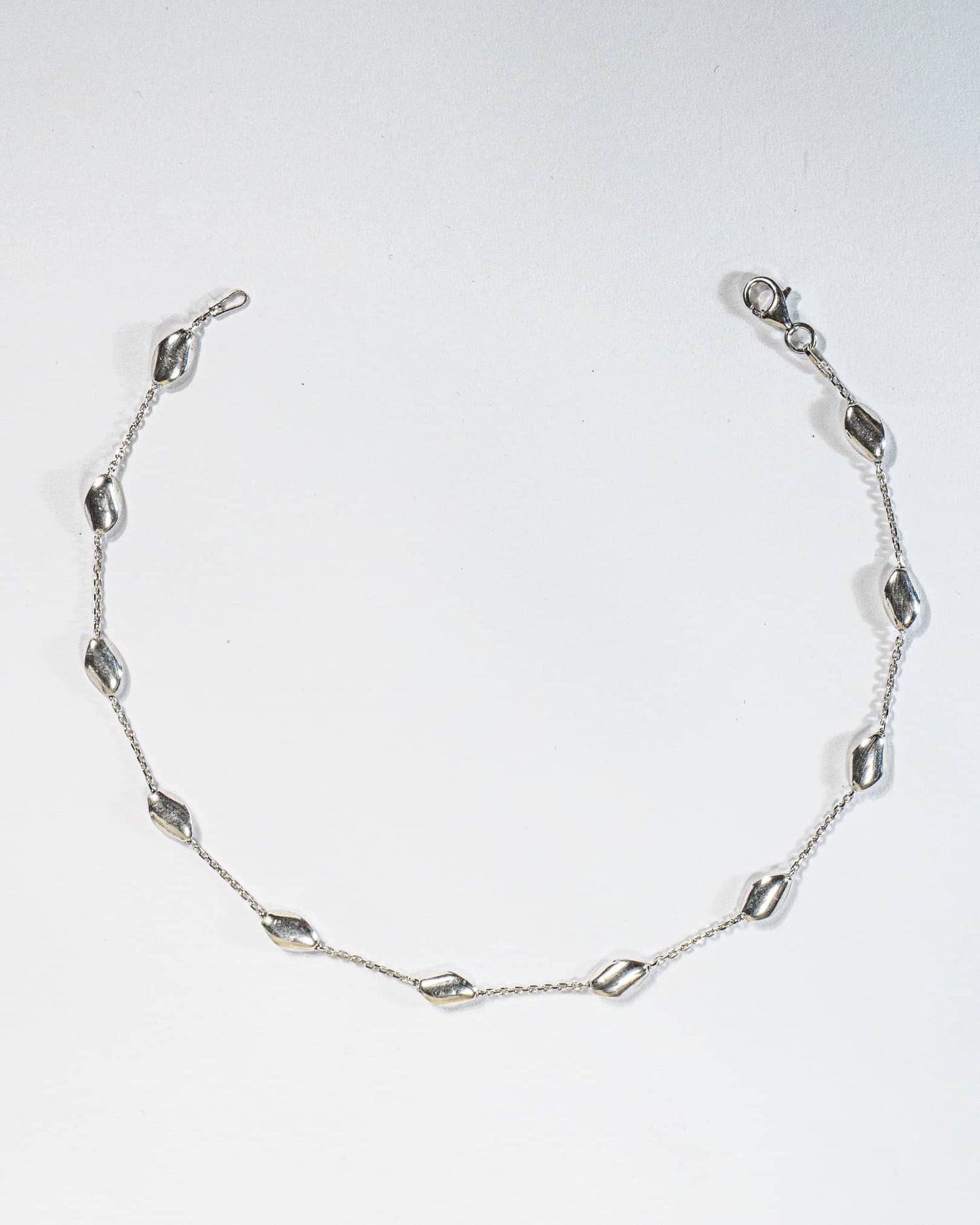 925 sterling silver minimalist anklet with spaced polished oval beads and lobster clasp.