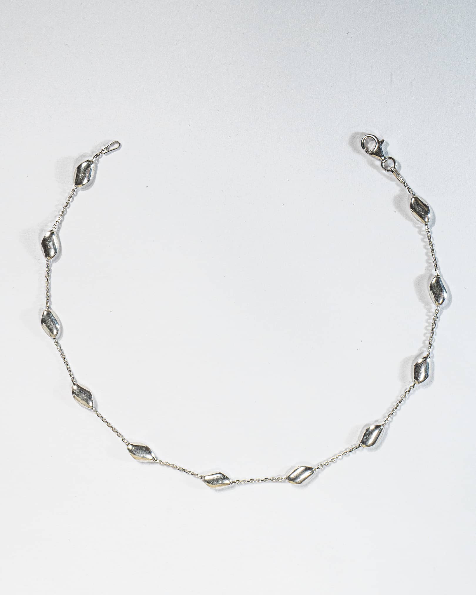 925 sterling silver minimalist anklet with spaced polished oval beads and lobster clasp.