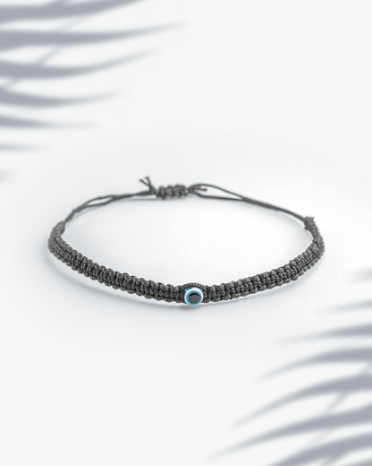 Black thread woven bracelet featuring a small blue evil eye bead with adjustable sliding knot.