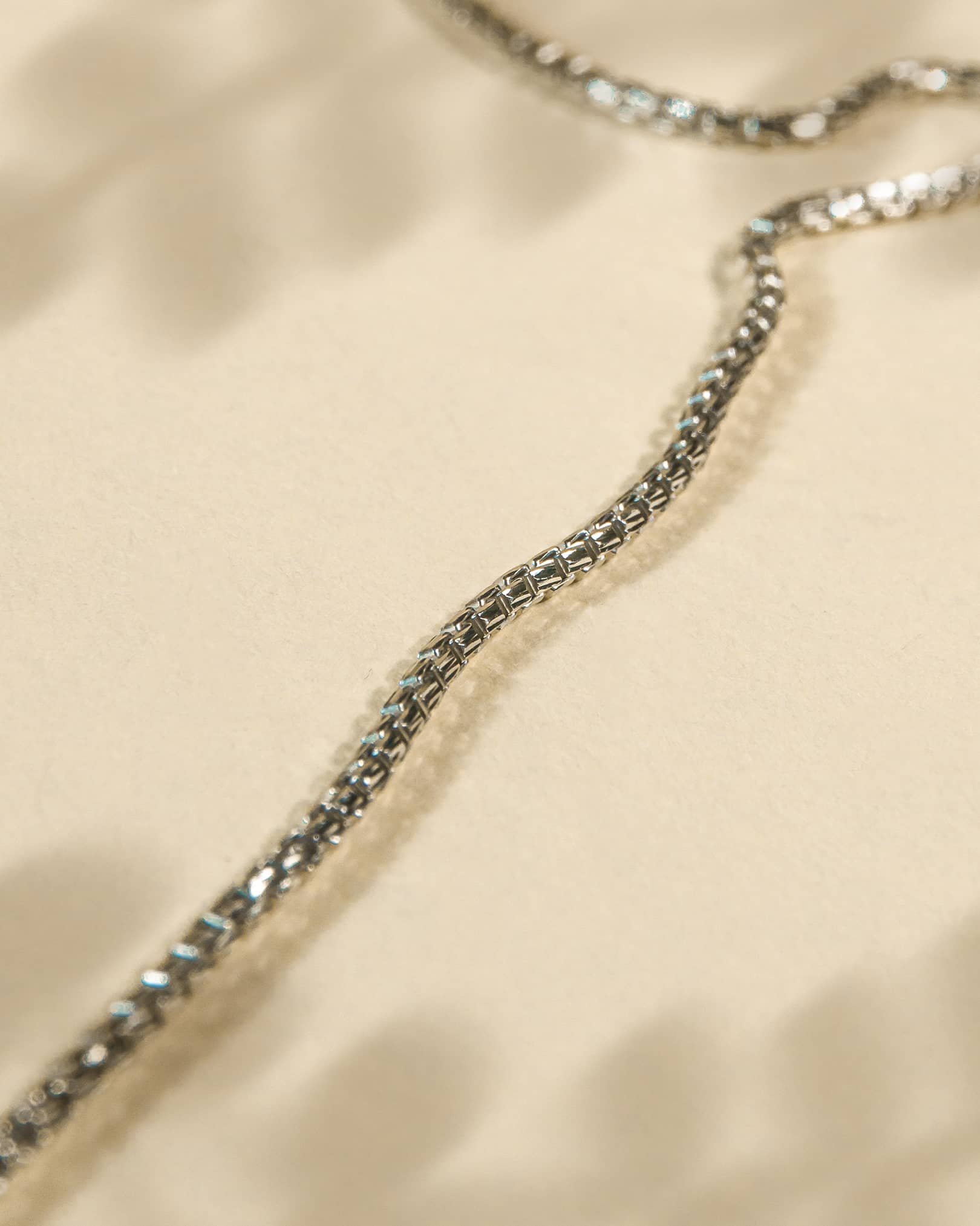 Close-up of a silver chain on a beige fabric background