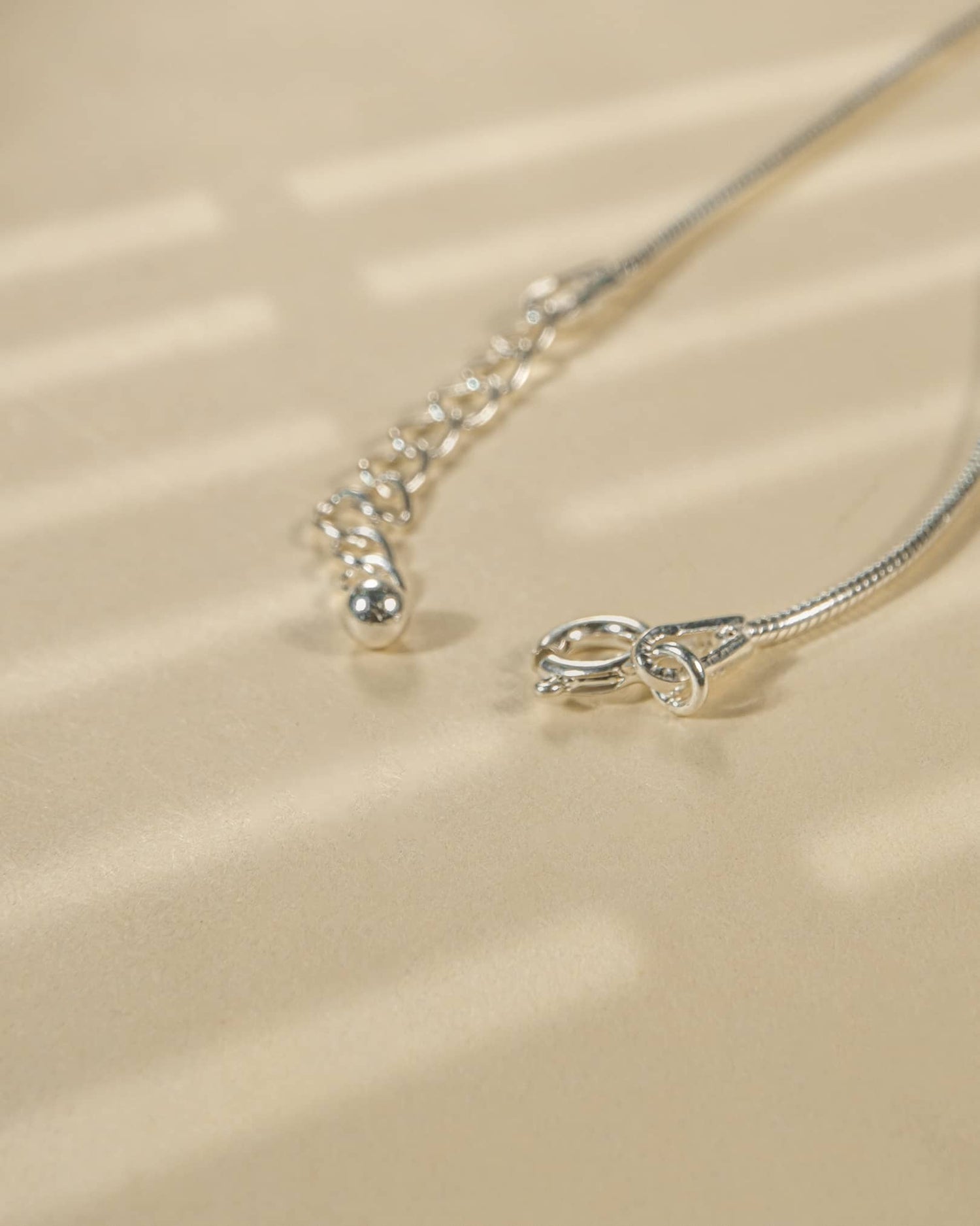 Close-up of a silver necklace on a beige fabric background