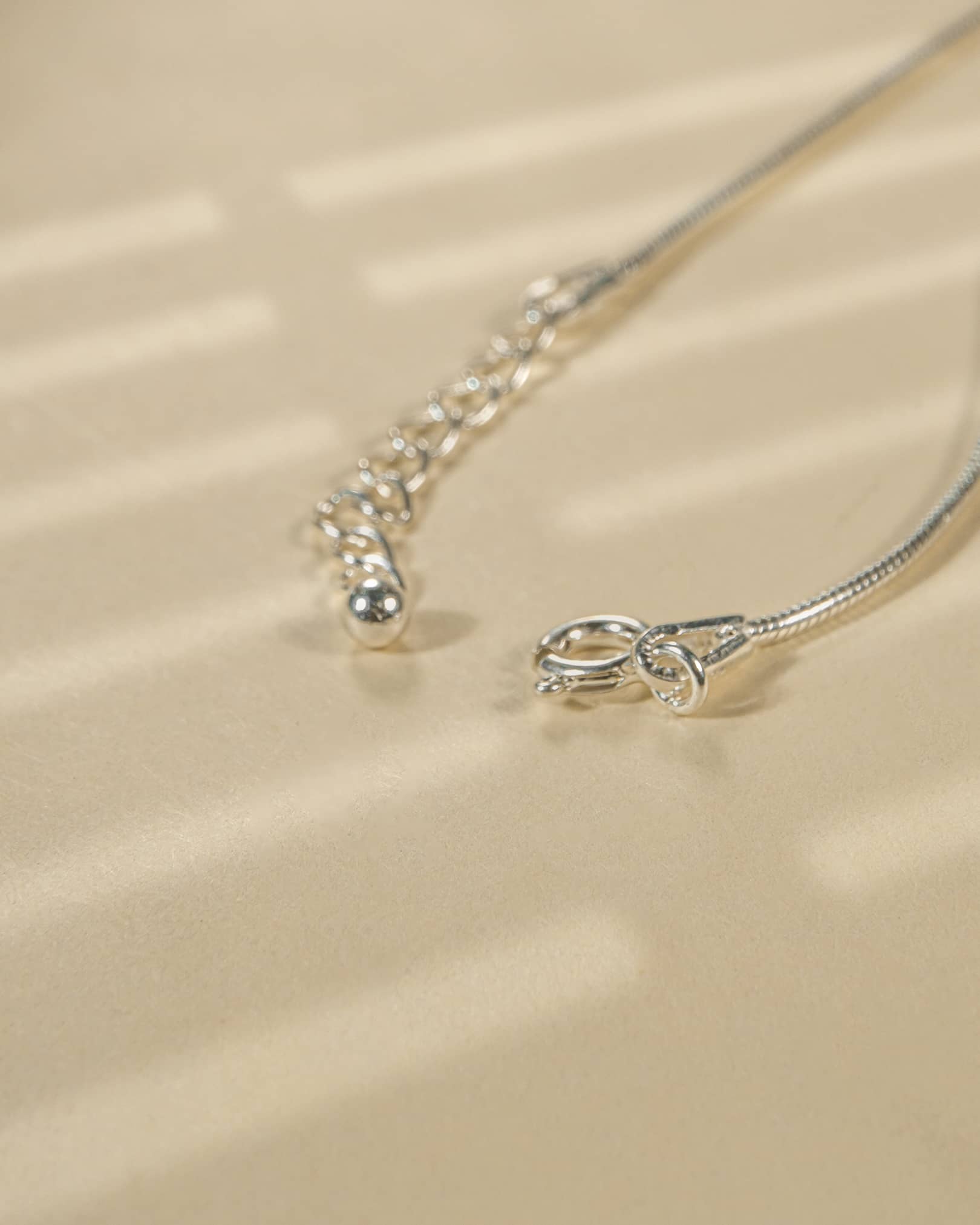 Close-up of a silver necklace on a beige fabric background