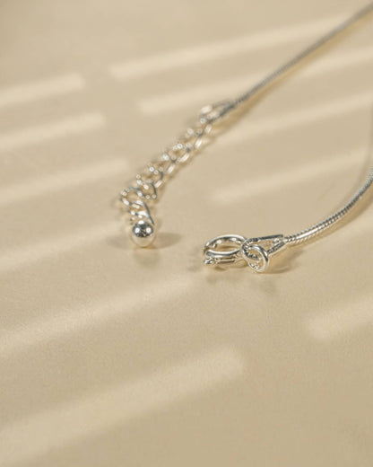 Close-up of a silver necklace on a beige fabric background