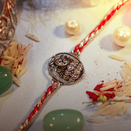 Ganesh Ji silver rakhi with detailed round charm on red-silver thread - Hardik Jewels