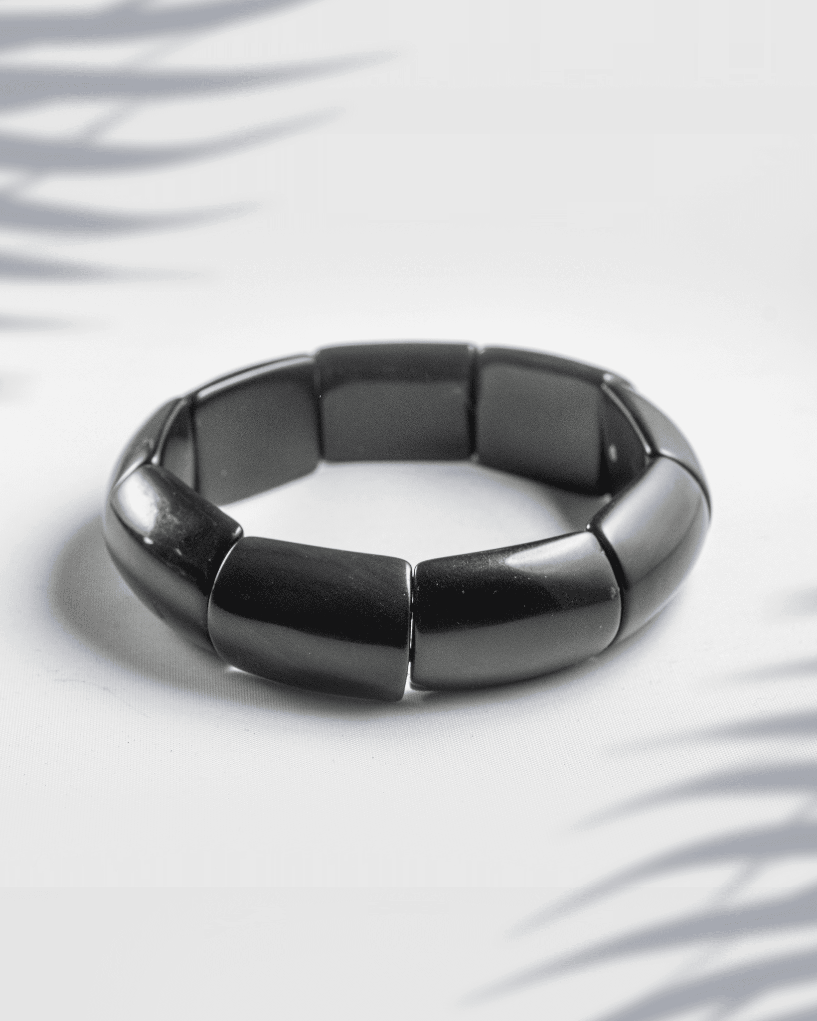 Glossy black rectangular tile fashion bracelet on a white background.