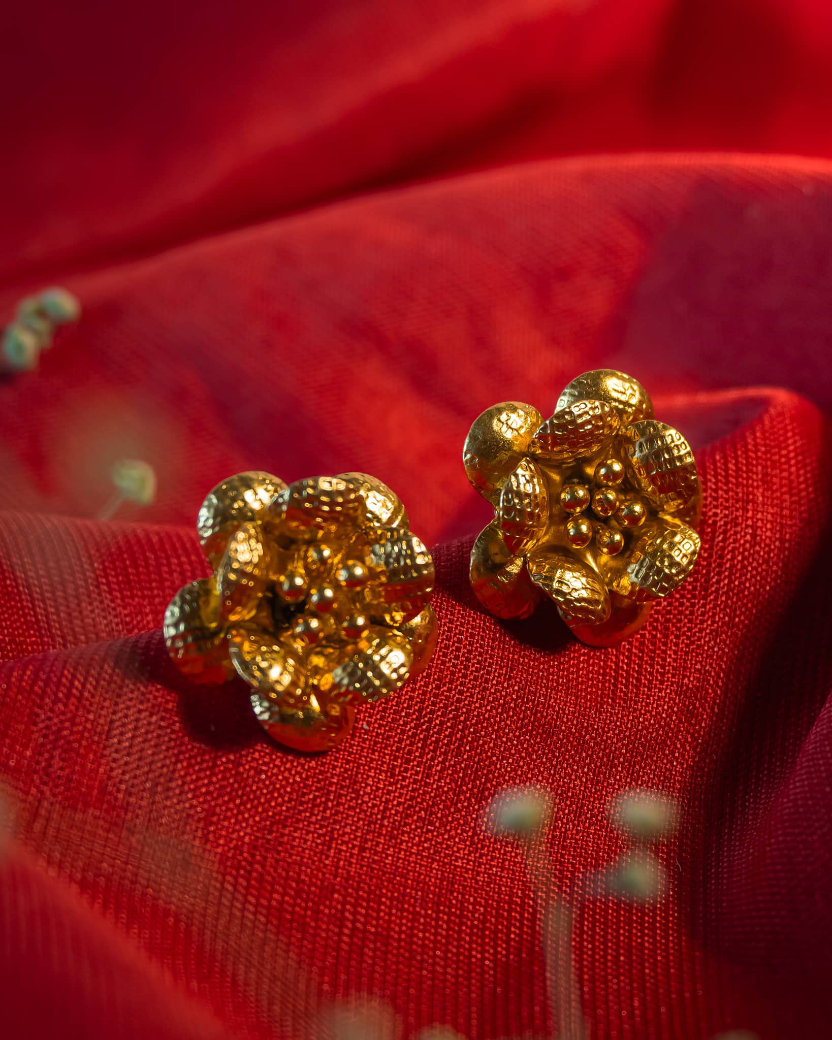 Gold plated 3D floral stud earrings featuring textured hammered petals and a beaded center.