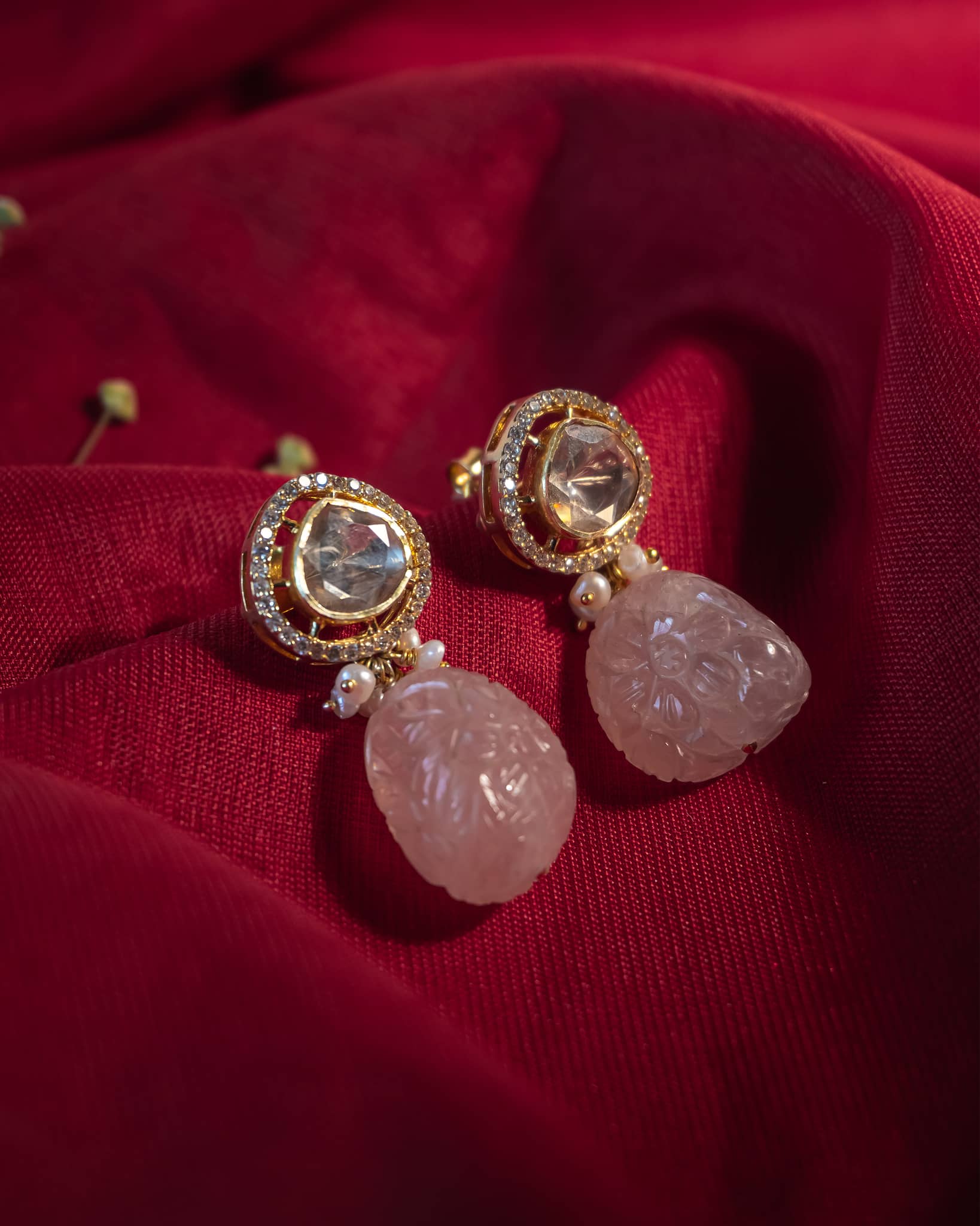 Gold plated 925 silver drop earrings featuring a carved natural rose quartz stone hanging from a polki stud.