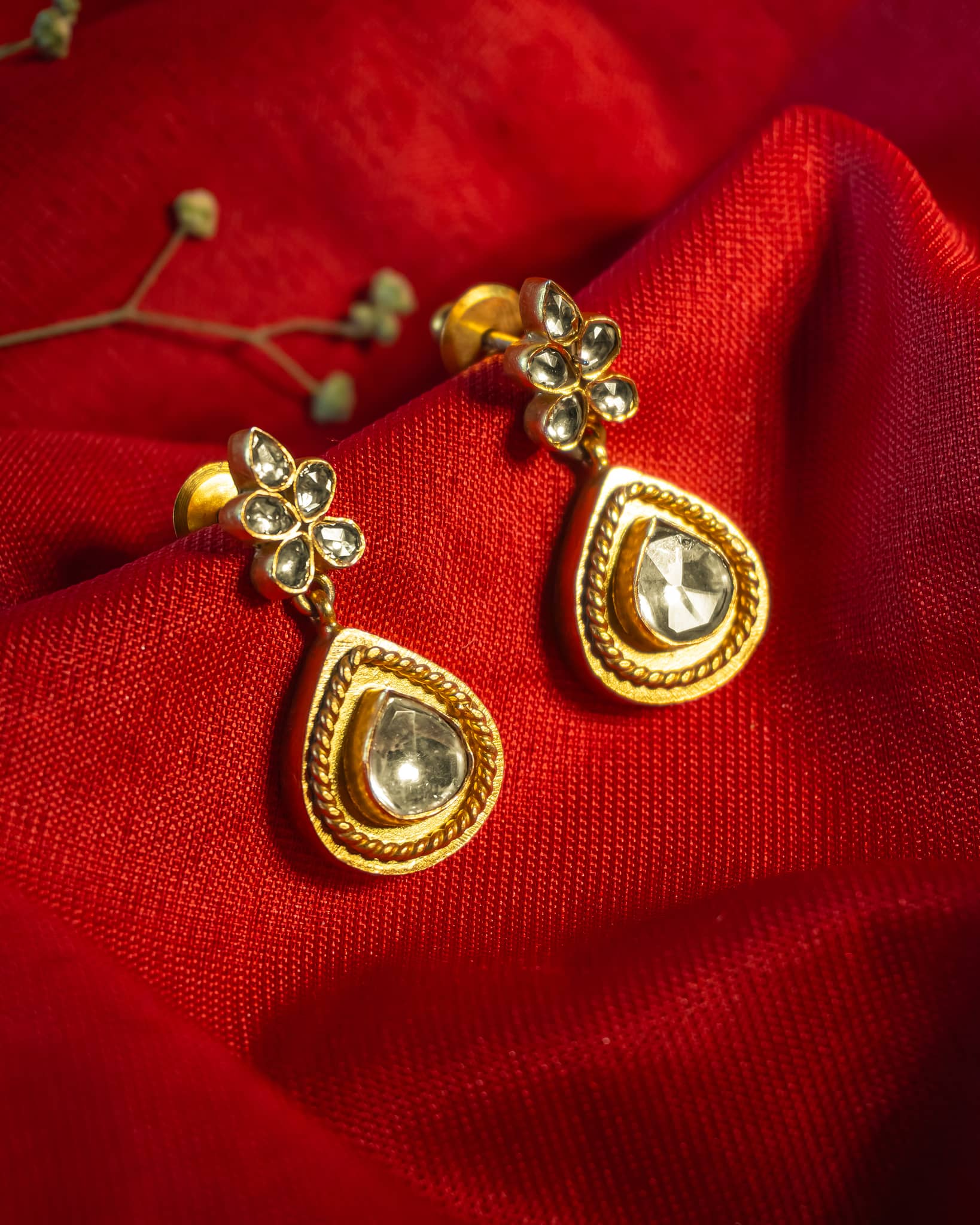 Gold plated drop earrings featuring a polki teardrop stone with rope texture border and floral stud.