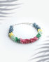 Multi precious gemstone bracelet featuring faceted blue green yellow and red beads with adjustable silver chain.