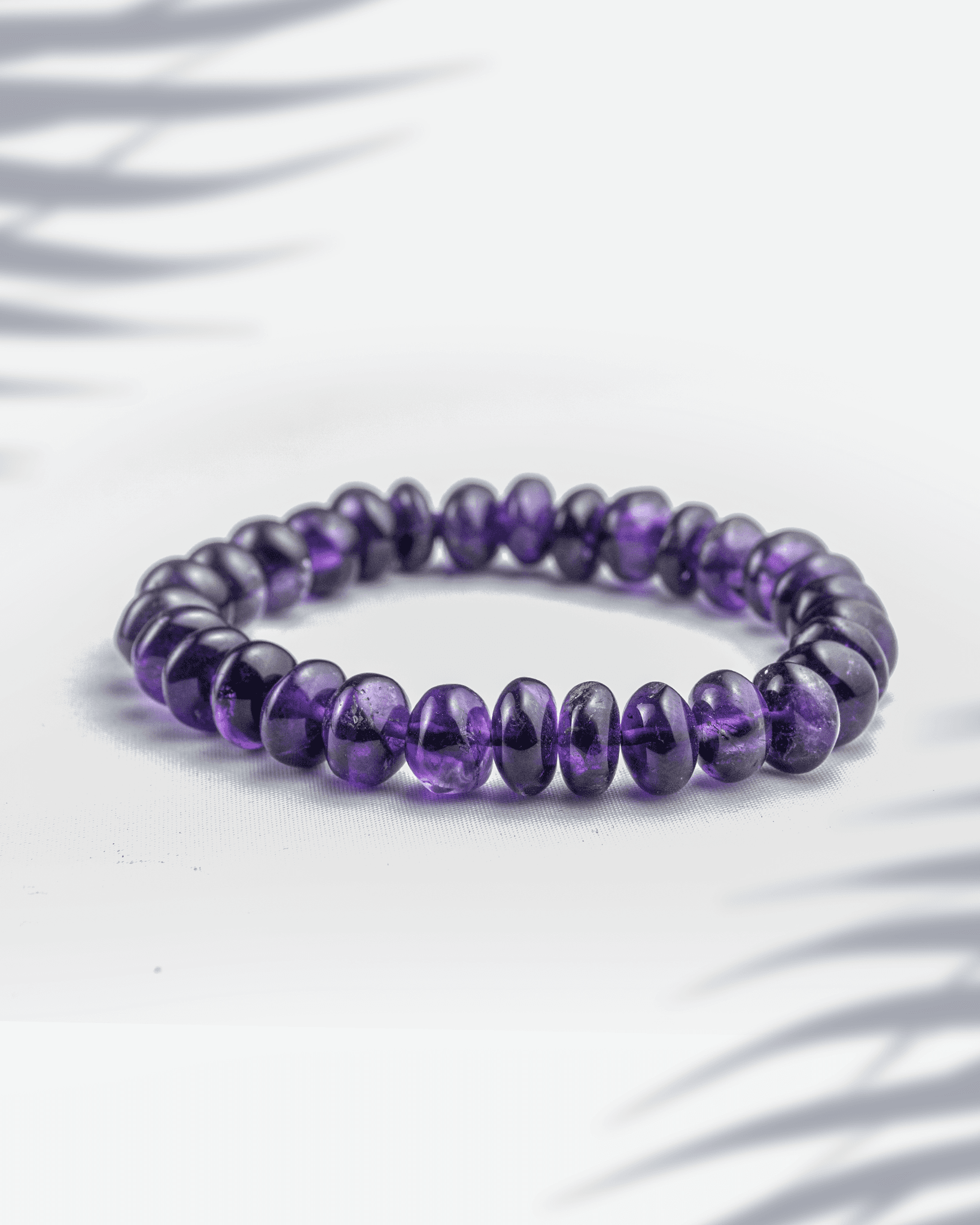 Natural Amethyst gemstone bracelet featuring smooth purple rondelle-shaped beads on a white background.