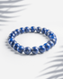 Natural Lapis Lazuli gemstone bracelet featuring deep blue beads with golden pyrite specks on a white background.