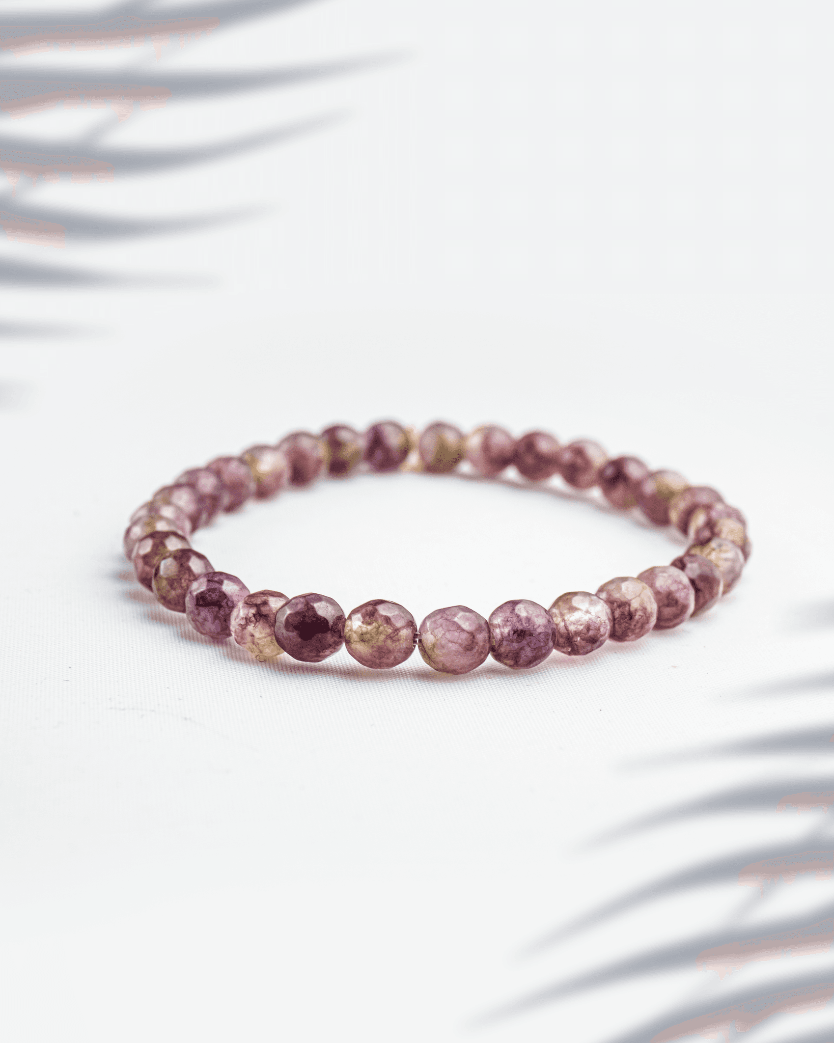 Natural Lepidolite gemstone bracelet featuring 6mm faceted purple beads on a white background.