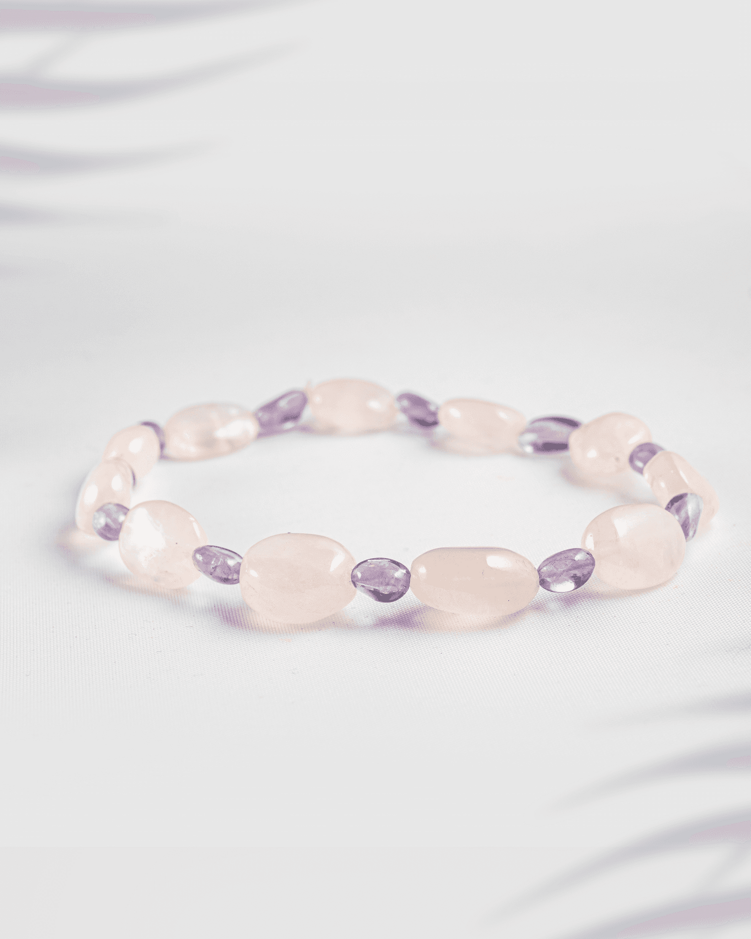 Natural Rose Quartz and Amethyst gemstone bracelet featuring tumbled oval beads on a white background.