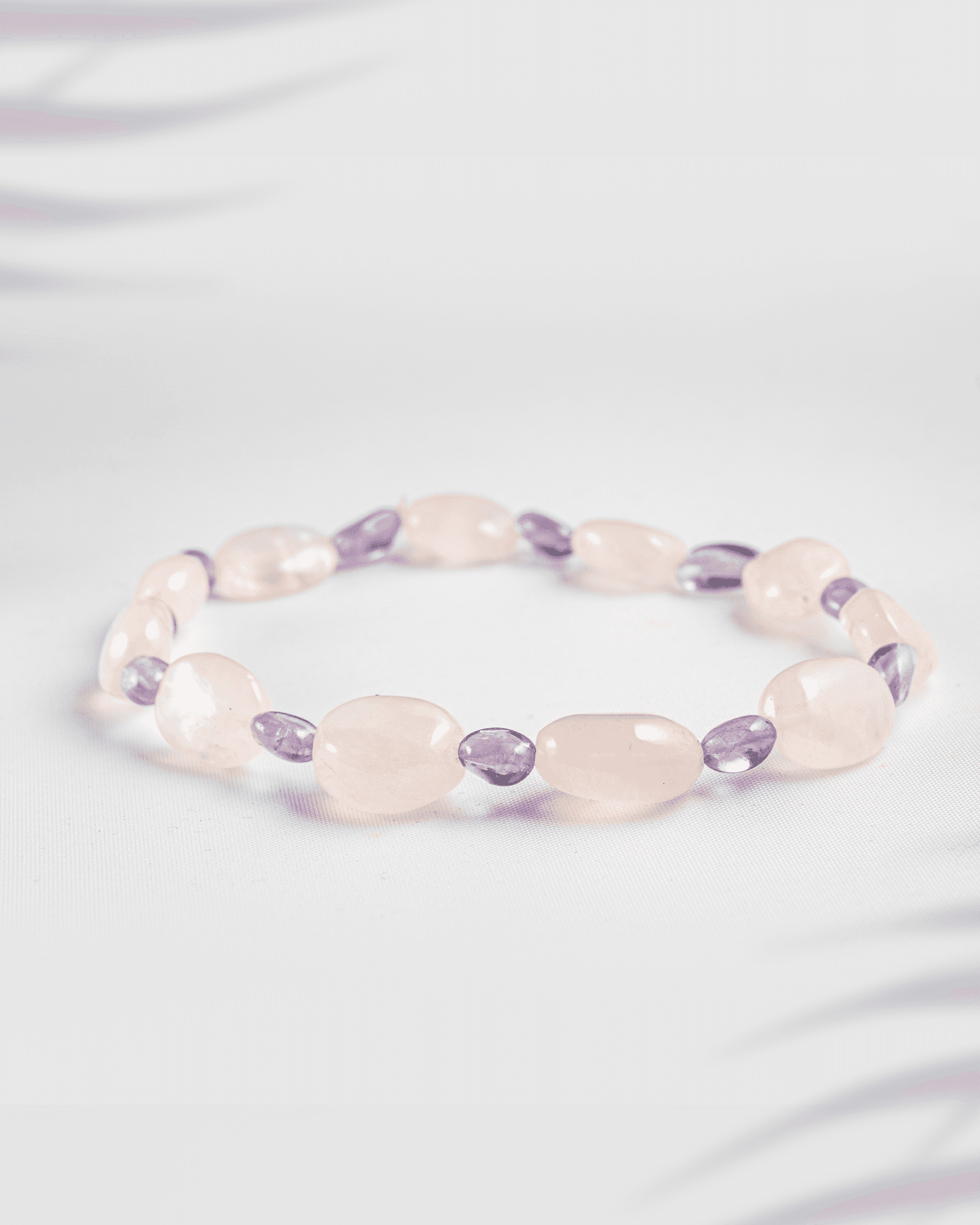 Natural Rose Quartz and Amethyst gemstone bracelet featuring tumbled oval beads on a white background.
