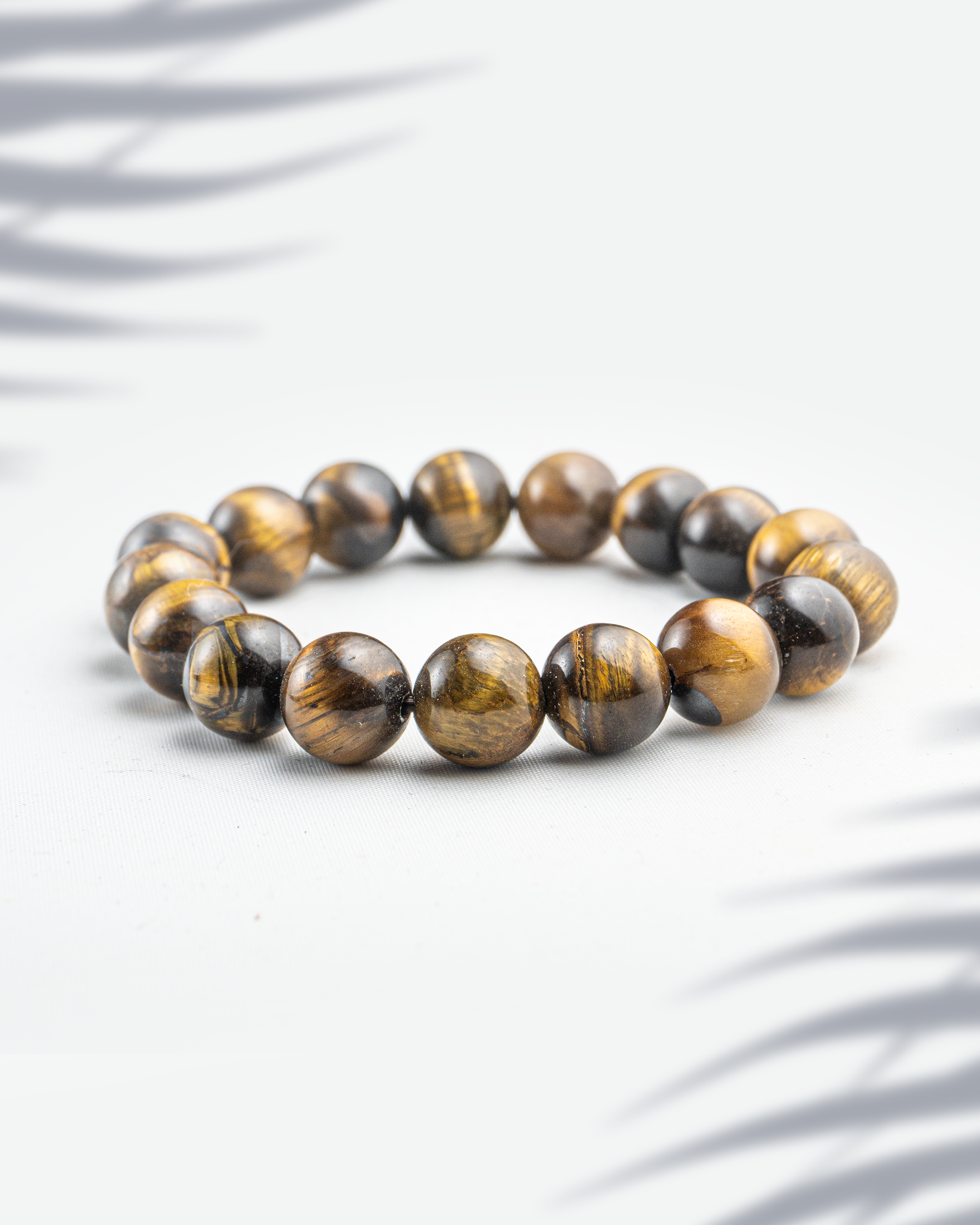 Natural Tiger Eye gemstone bracelet with golden-brown chatoyant bands on a white background.