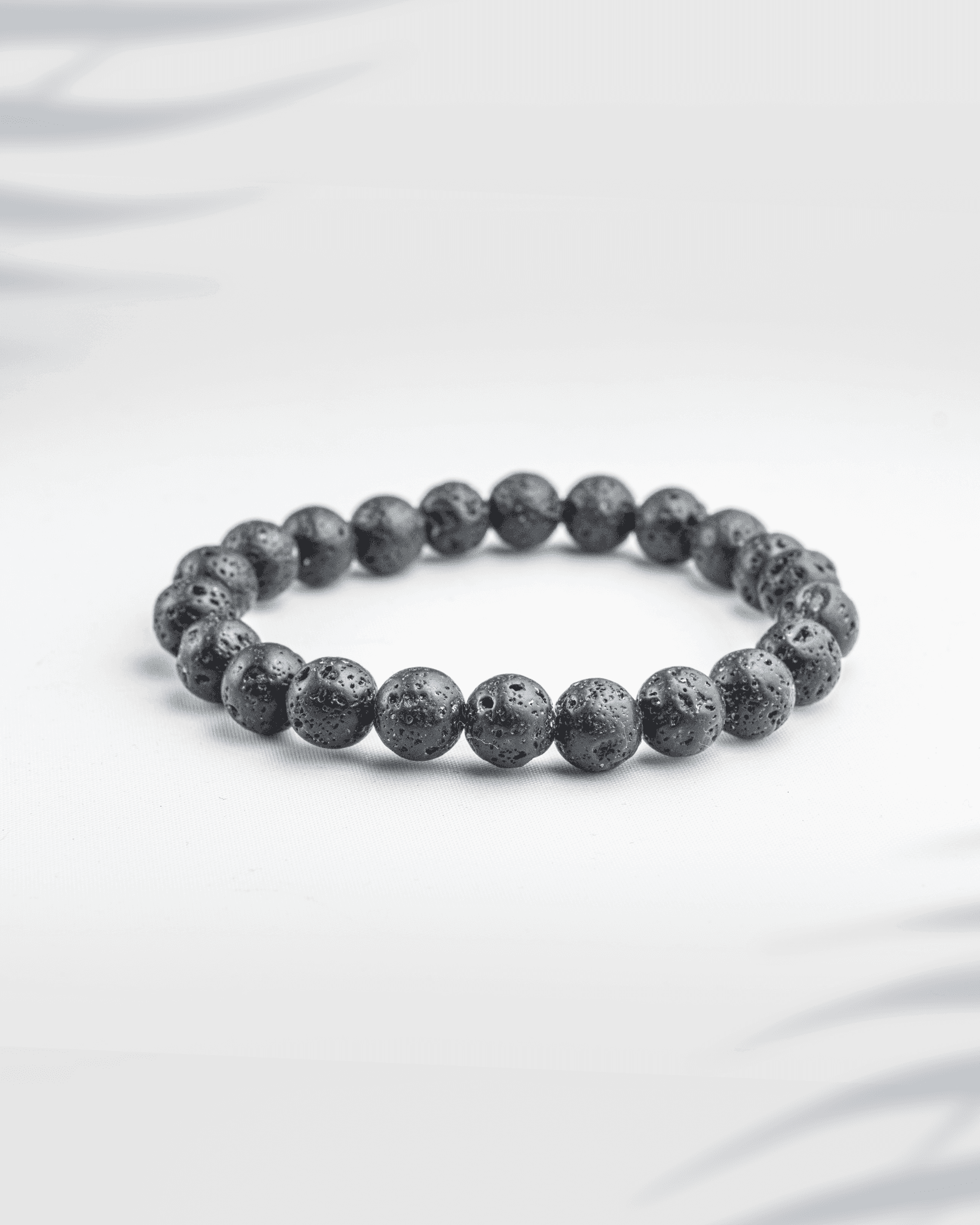 Natural black lava stone bracelet featuring porous volcanic beads on a white background.