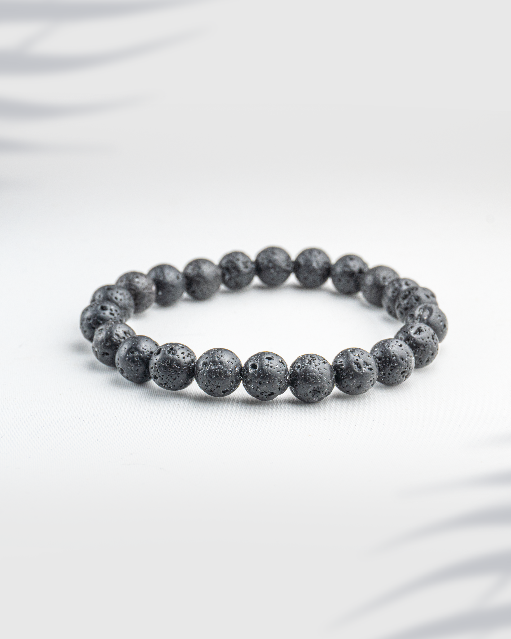 Natural black lava stone bracelet featuring porous volcanic beads on a white background.