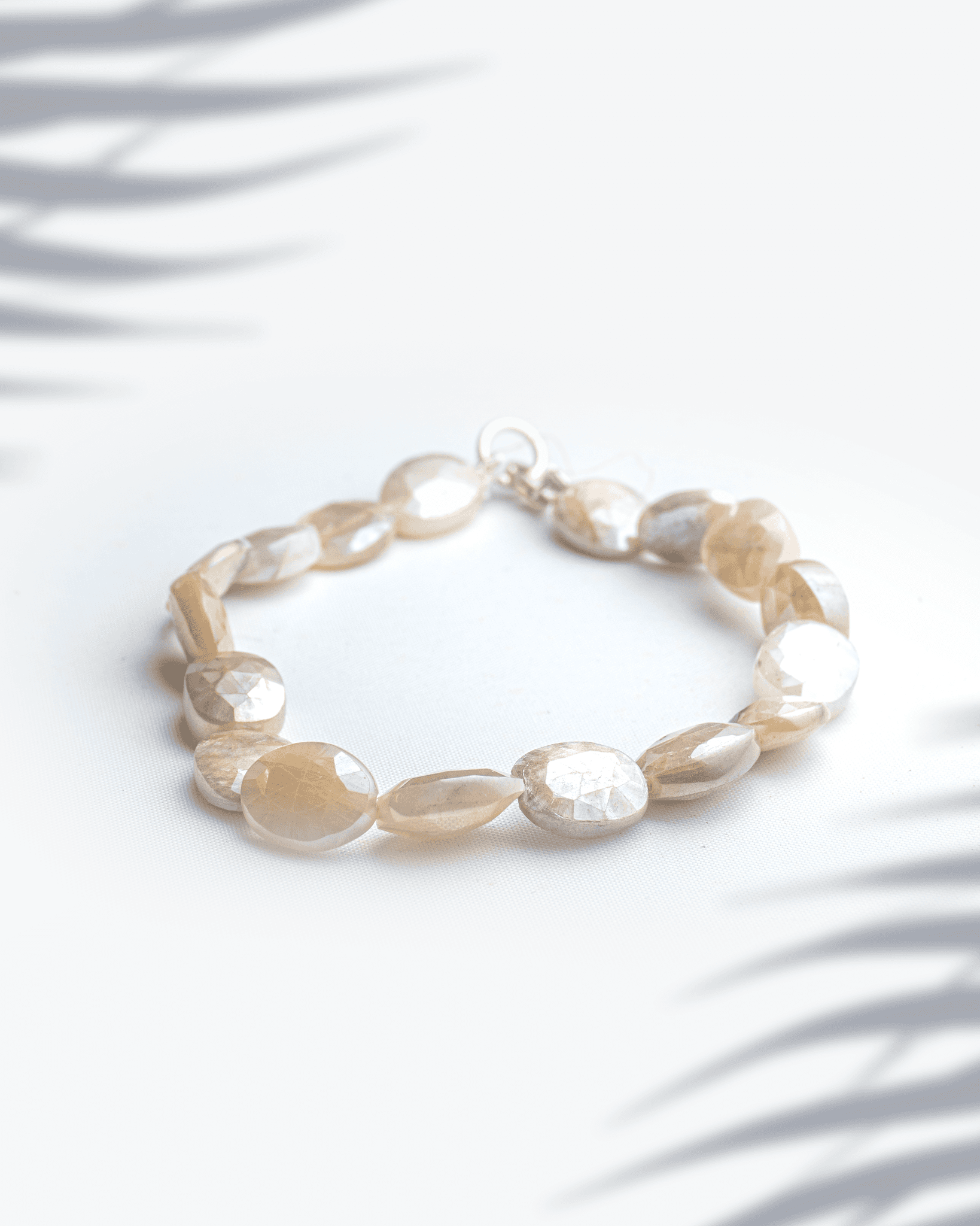 Natural multi-color faceted moonstone bracelet with silver lobster clasp featuring peach and grey oval beads.