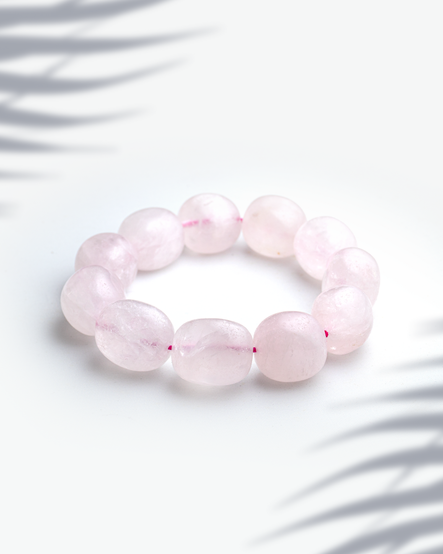 Natural rose quartz gemstone bracelet featuring organic tumbled pink nugget beads on a white background
