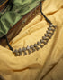 Oxidized 925 sterling silver heart motif choker necklace with ghungroos strung on a black thread, displayed on a yellow background.