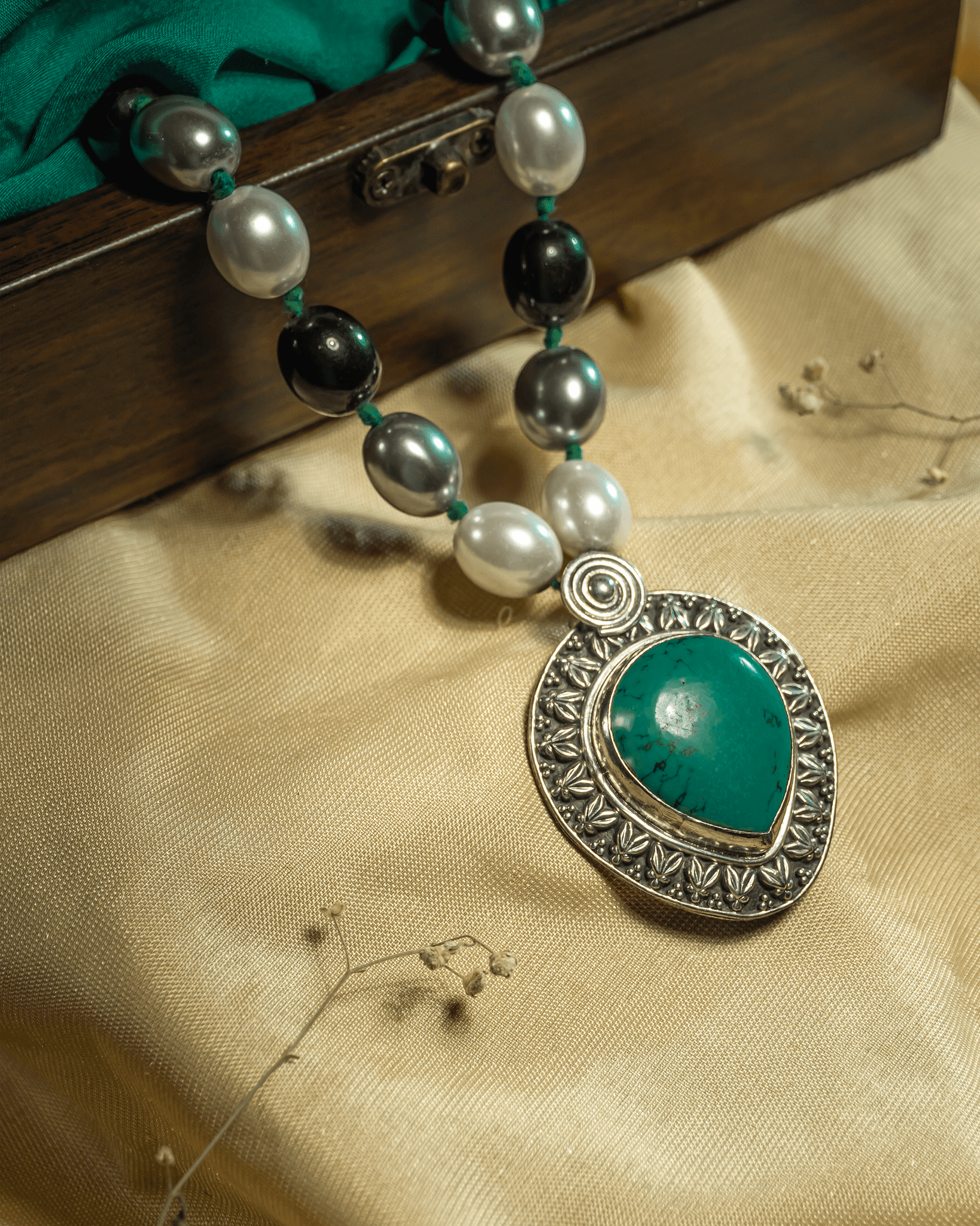 Oxidized 925 sterling silver necklace featuring a turquoise teardrop pendant and a strand of black grey and white beads.
