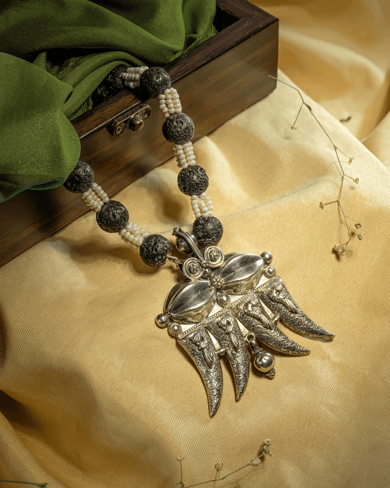 Oxidized 925 sterling silver tribal pendant necklace featuring a 4-claw design strung on black textured lava beads and white pearls.